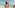 Smiling man lifts happy child high on a sunny beach by the ocean.