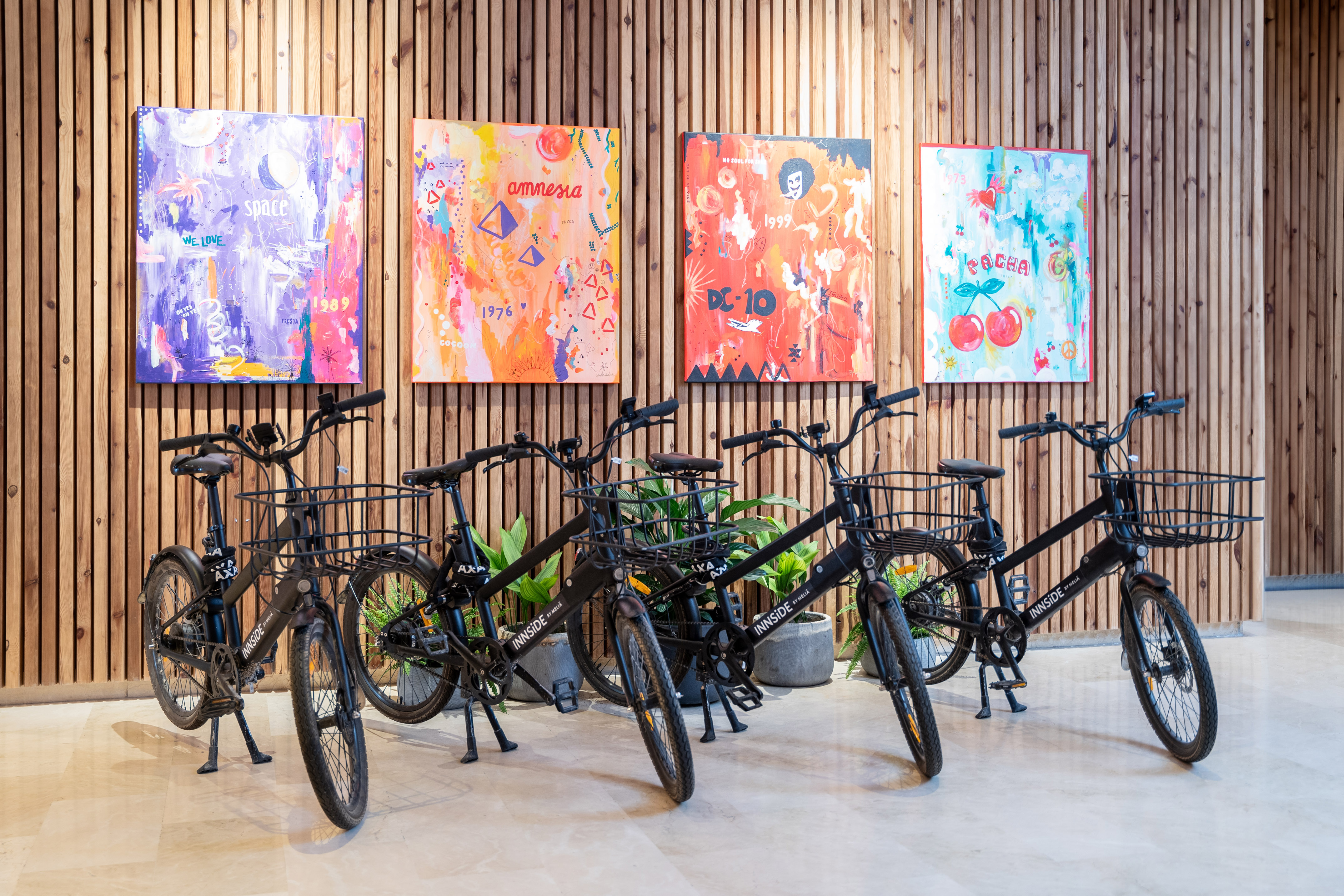 INNSIDE by MELIA rental bikes with baskets, vibrant art on a wood-slat wall.