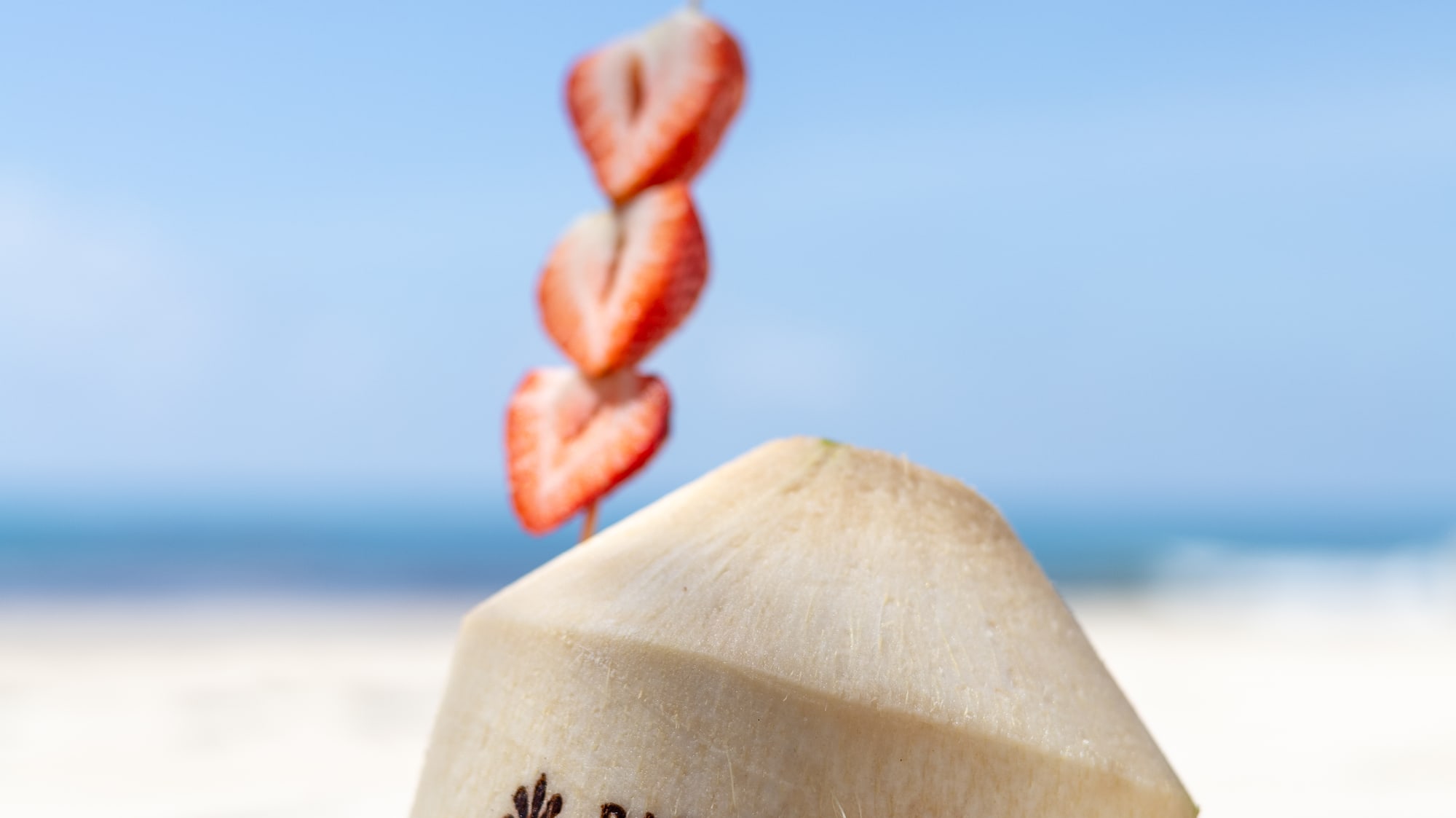 Paradisus by Melia branded coconut drink with strawberries on a beach.