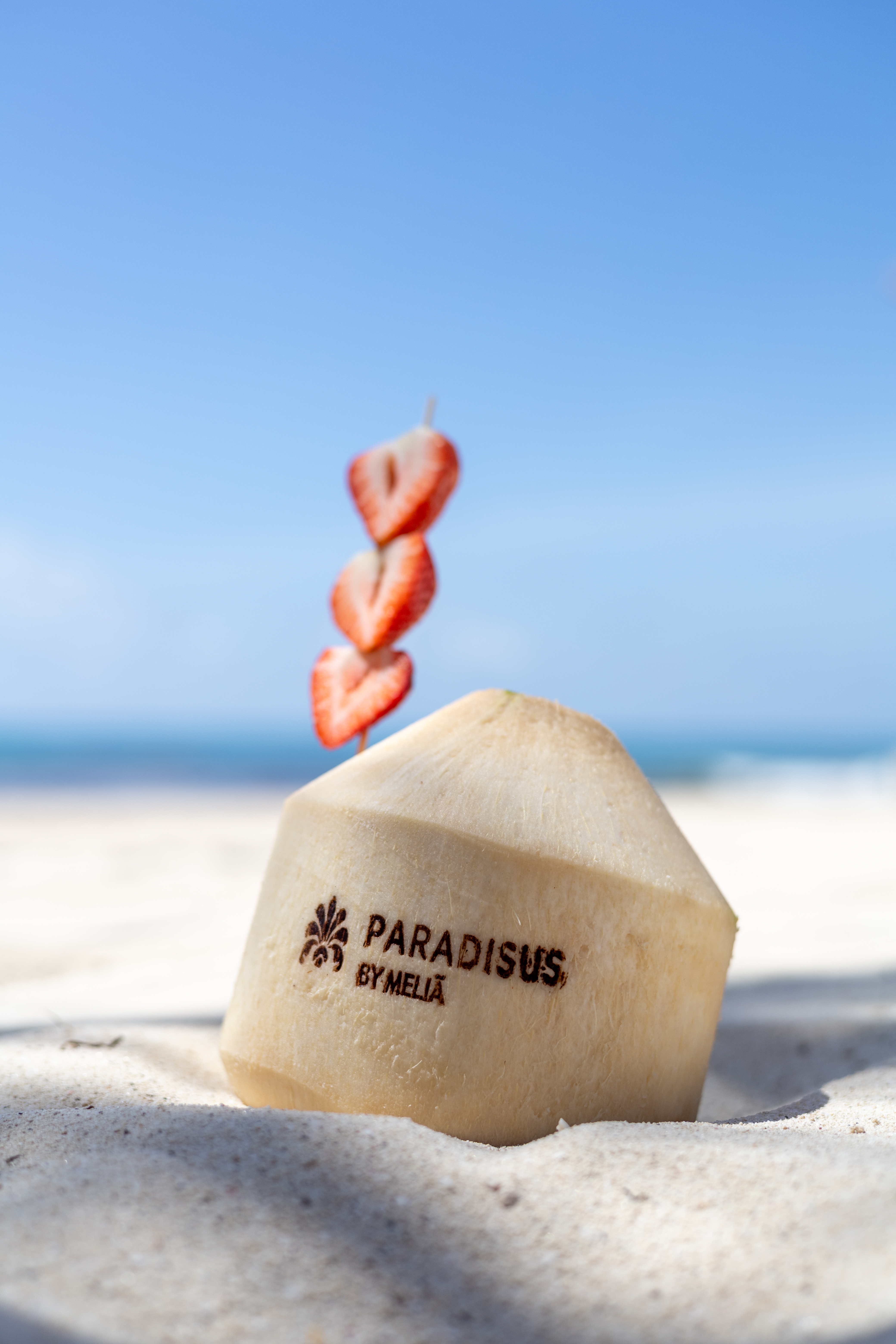Paradisus by Melia branded coconut drink with strawberries on a beach.