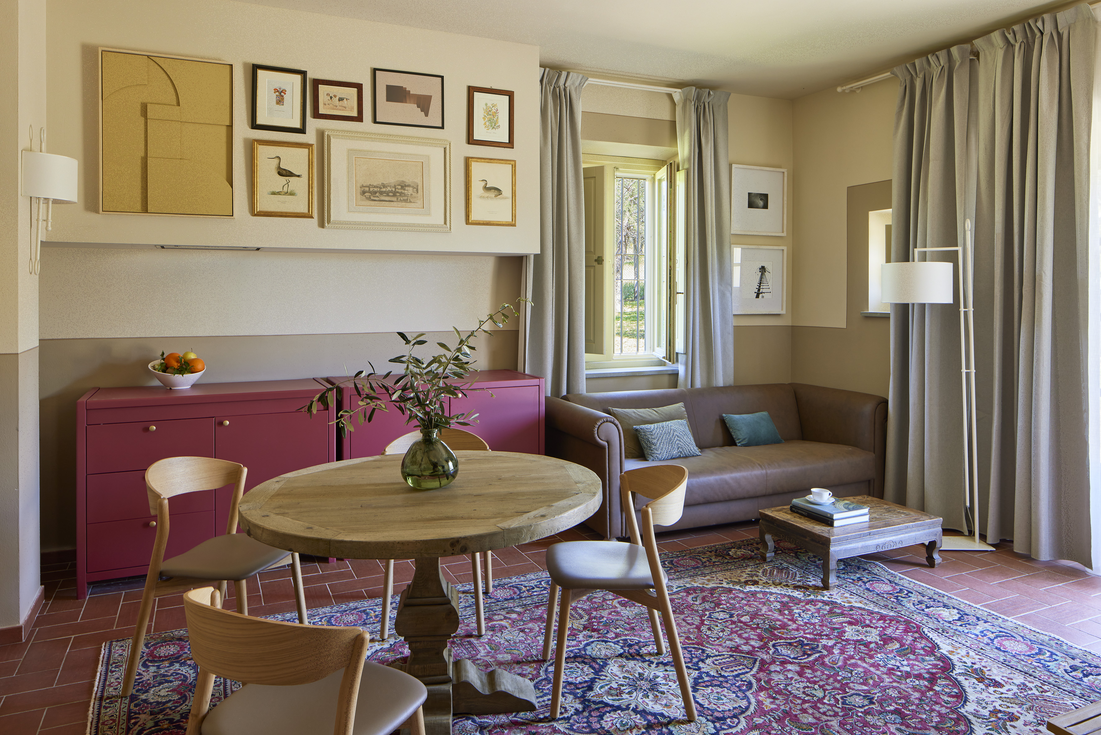 Living room with brown sofa, wooden table, red patterned rug, and framed art.