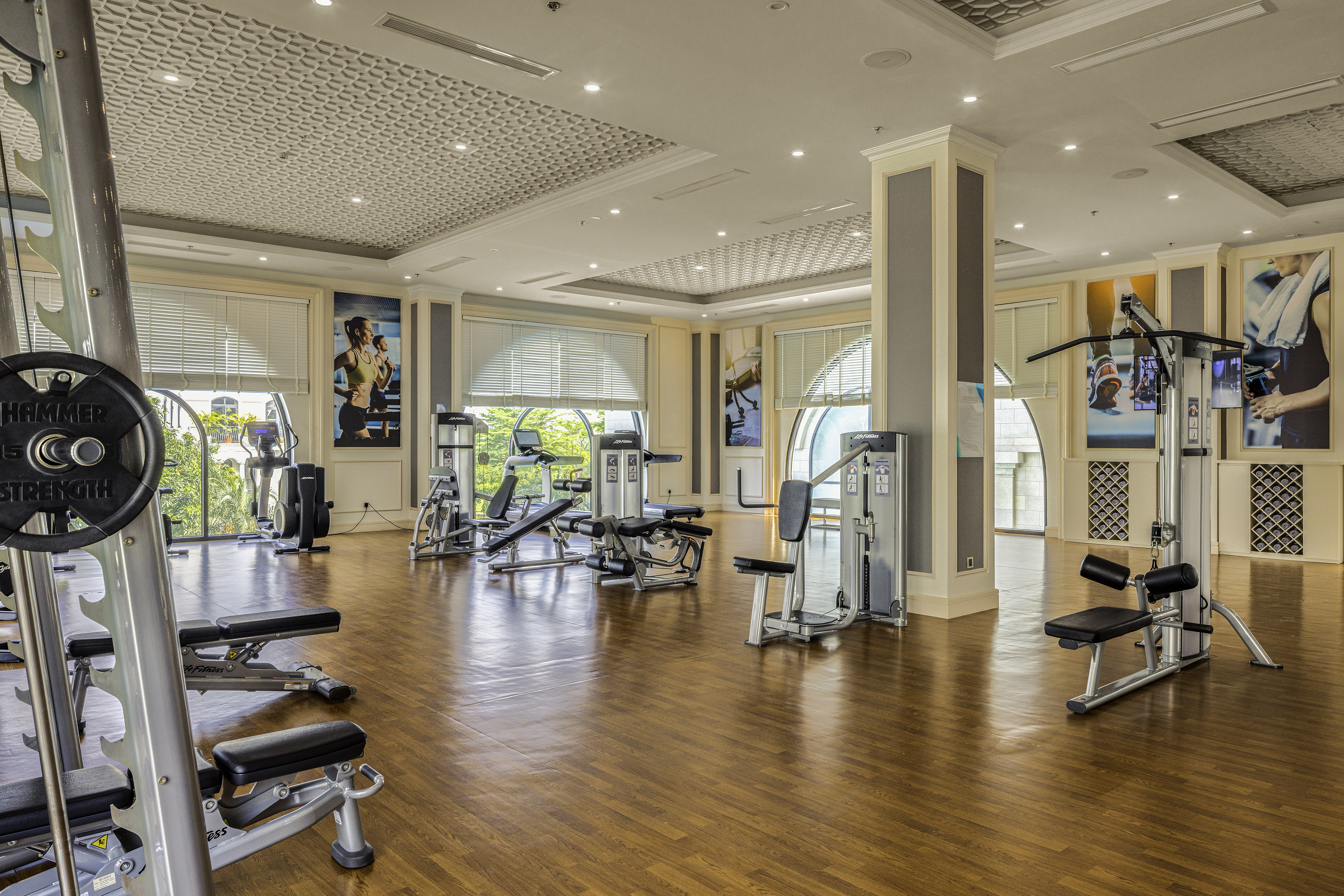 Bright, modern gym with cardio and strength training equipment on wood floor.