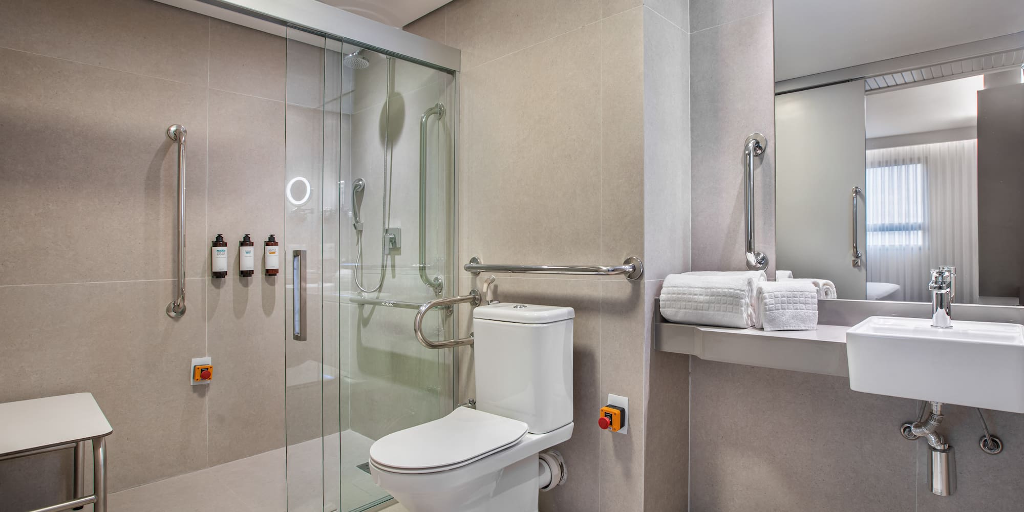 Handicap accessible bathroom with roll-in shower, toilet, and grab bars.