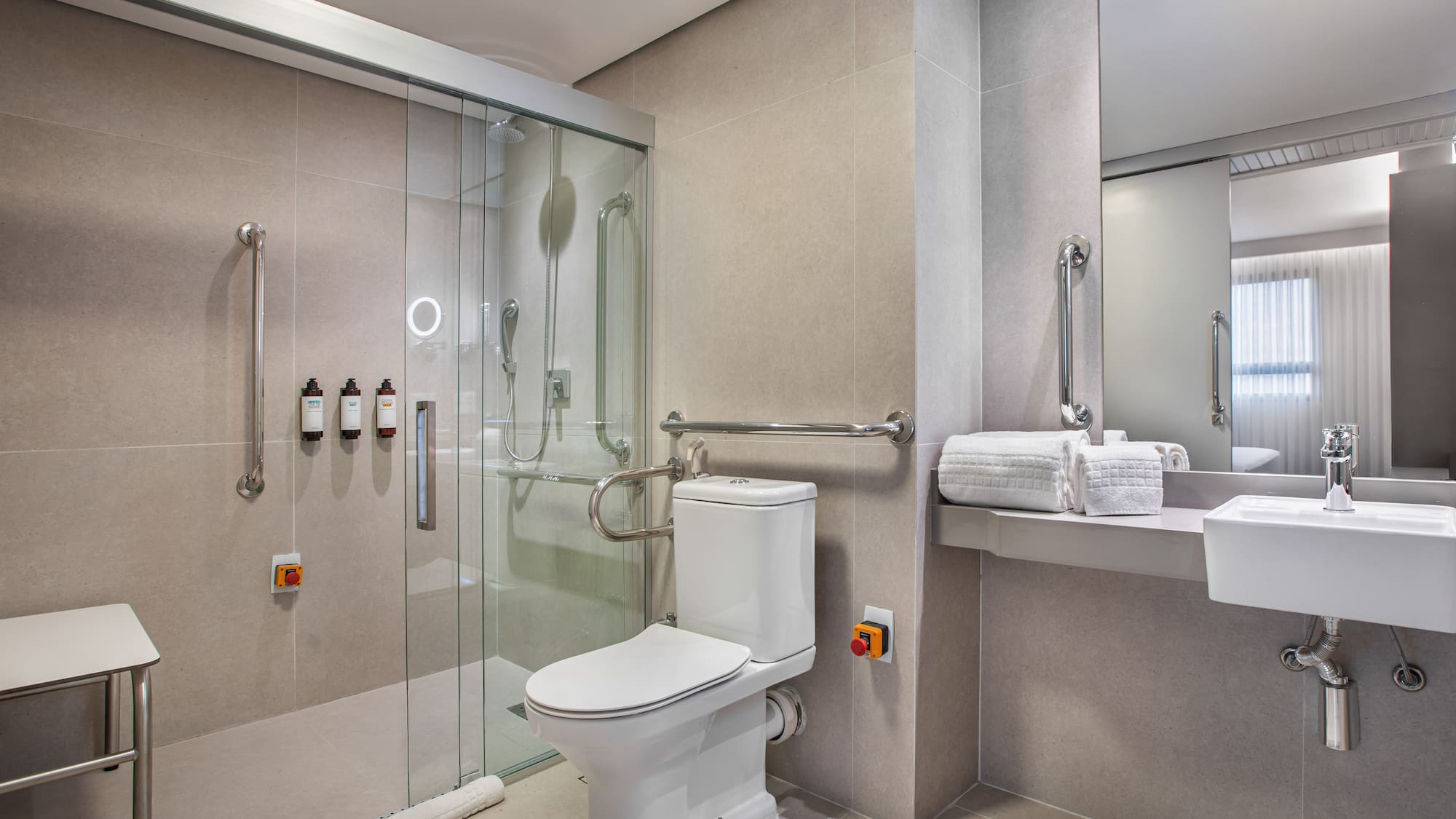 Handicap accessible bathroom with roll-in shower, toilet, and grab bars.