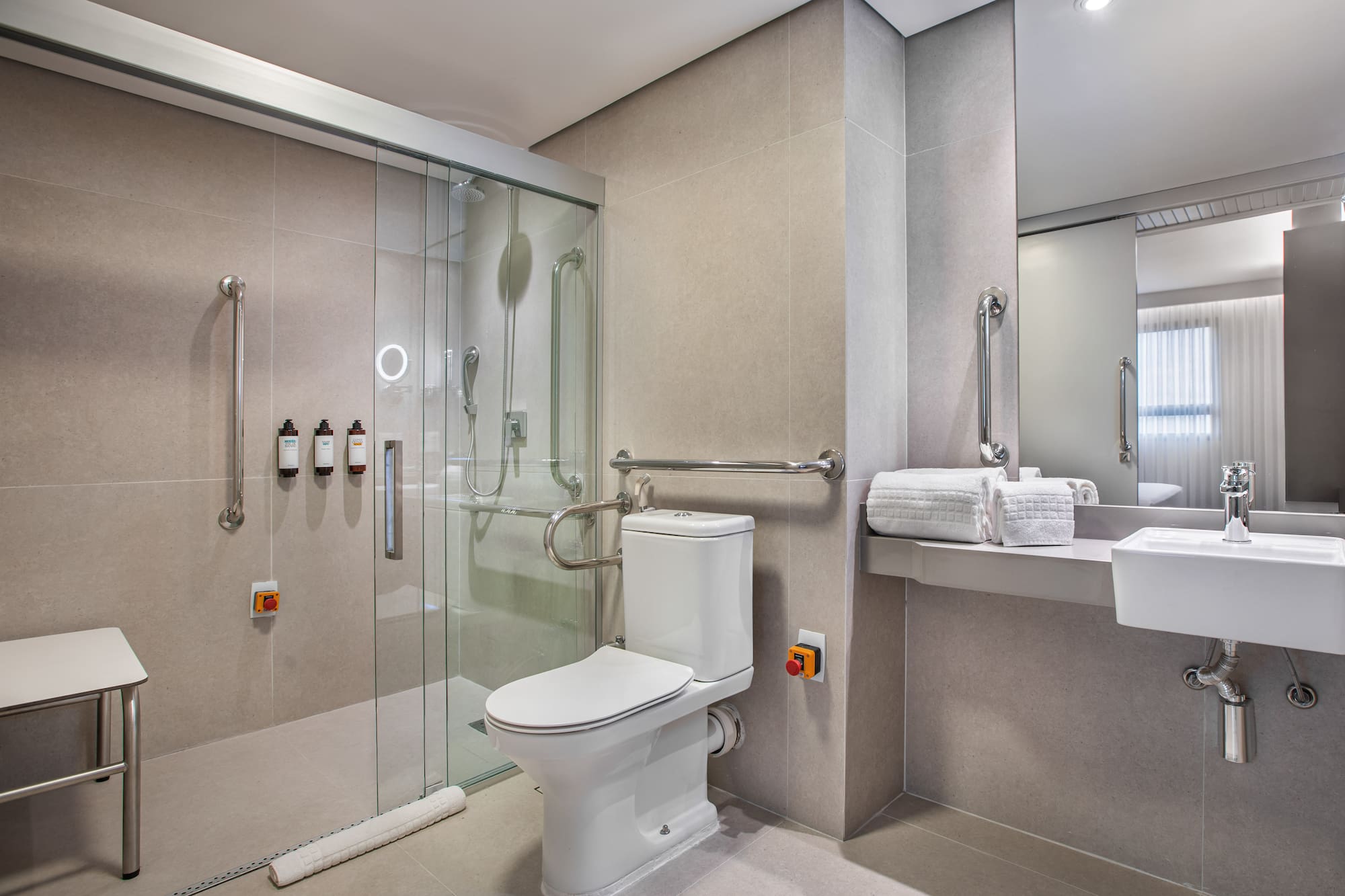 Handicap accessible bathroom with roll-in shower, toilet, and grab bars.