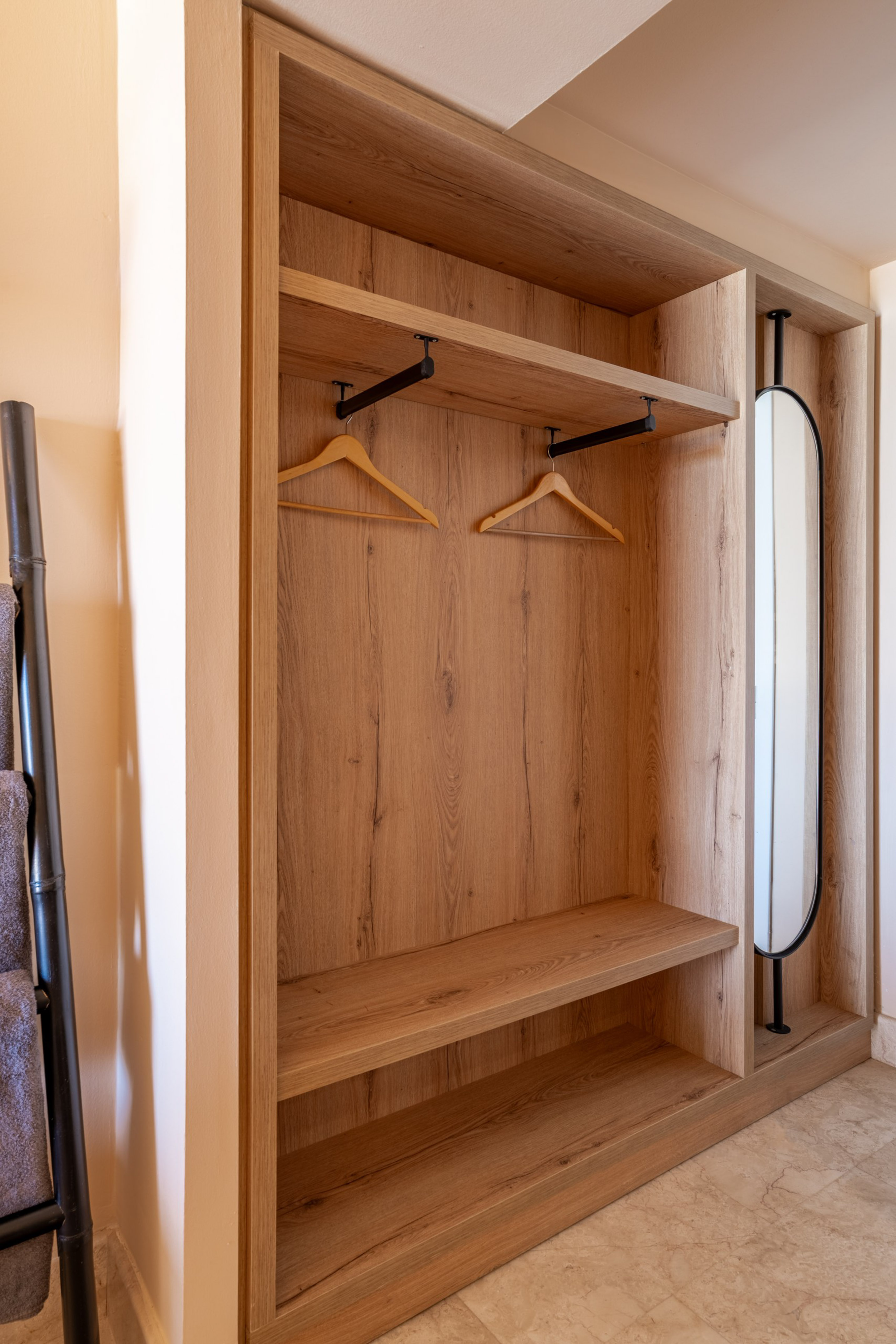 Modern light wood open wardrobe with hangers, shelves, and integrated mirror.