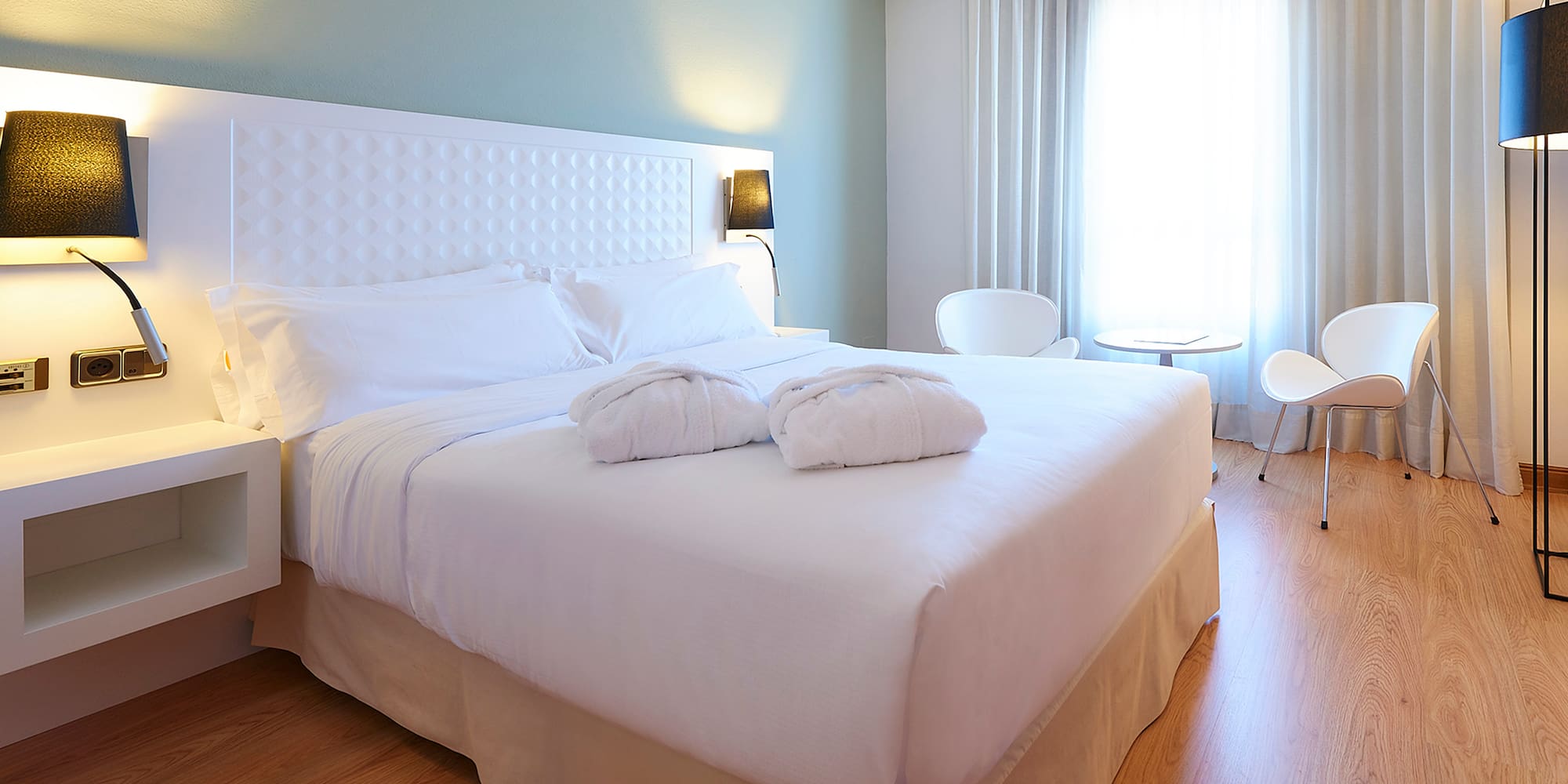 a bed with white sheets and pillows in a room