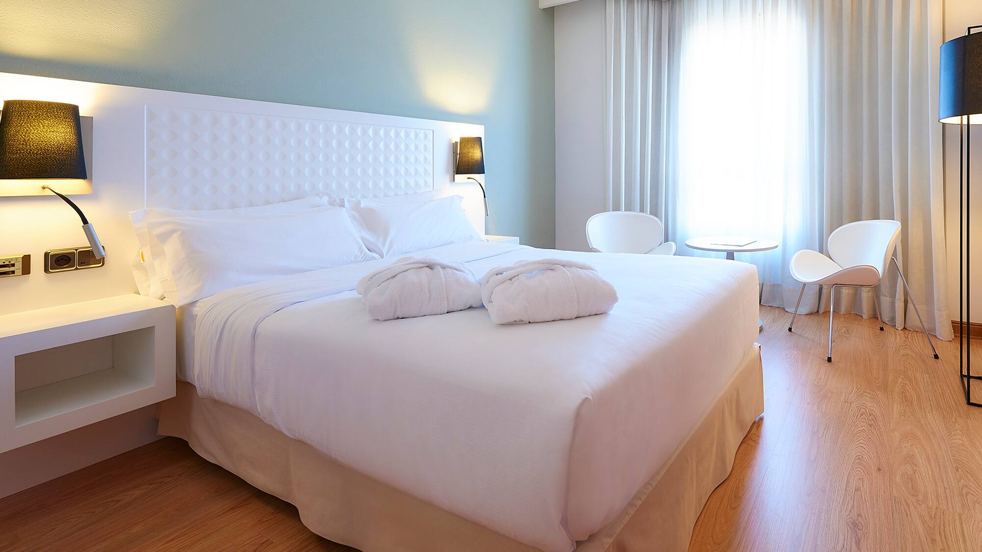 a bed with white sheets and pillows in a room