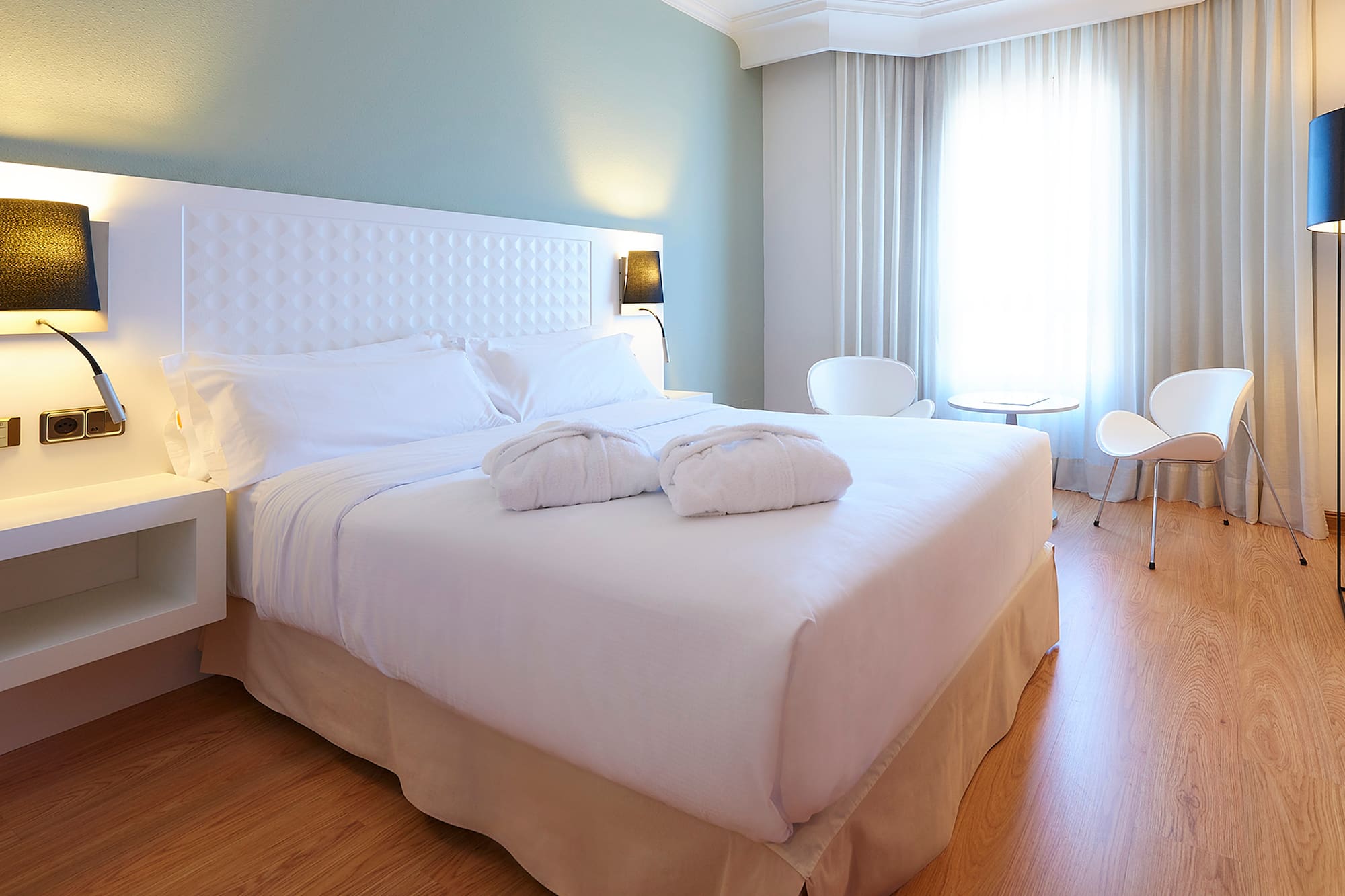 a bed with white sheets and pillows in a room