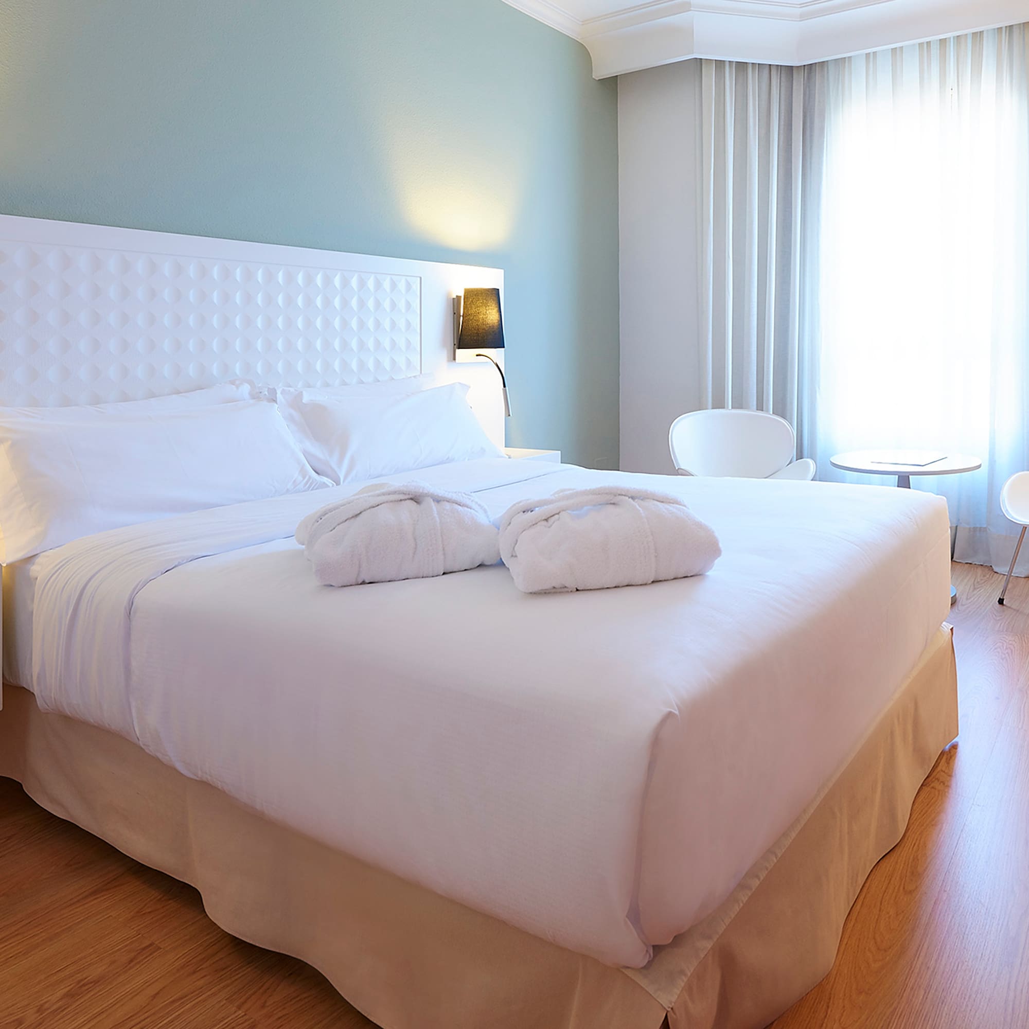 a bed with white sheets and pillows in a room