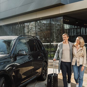 a man and woman walking with luggage outside a building