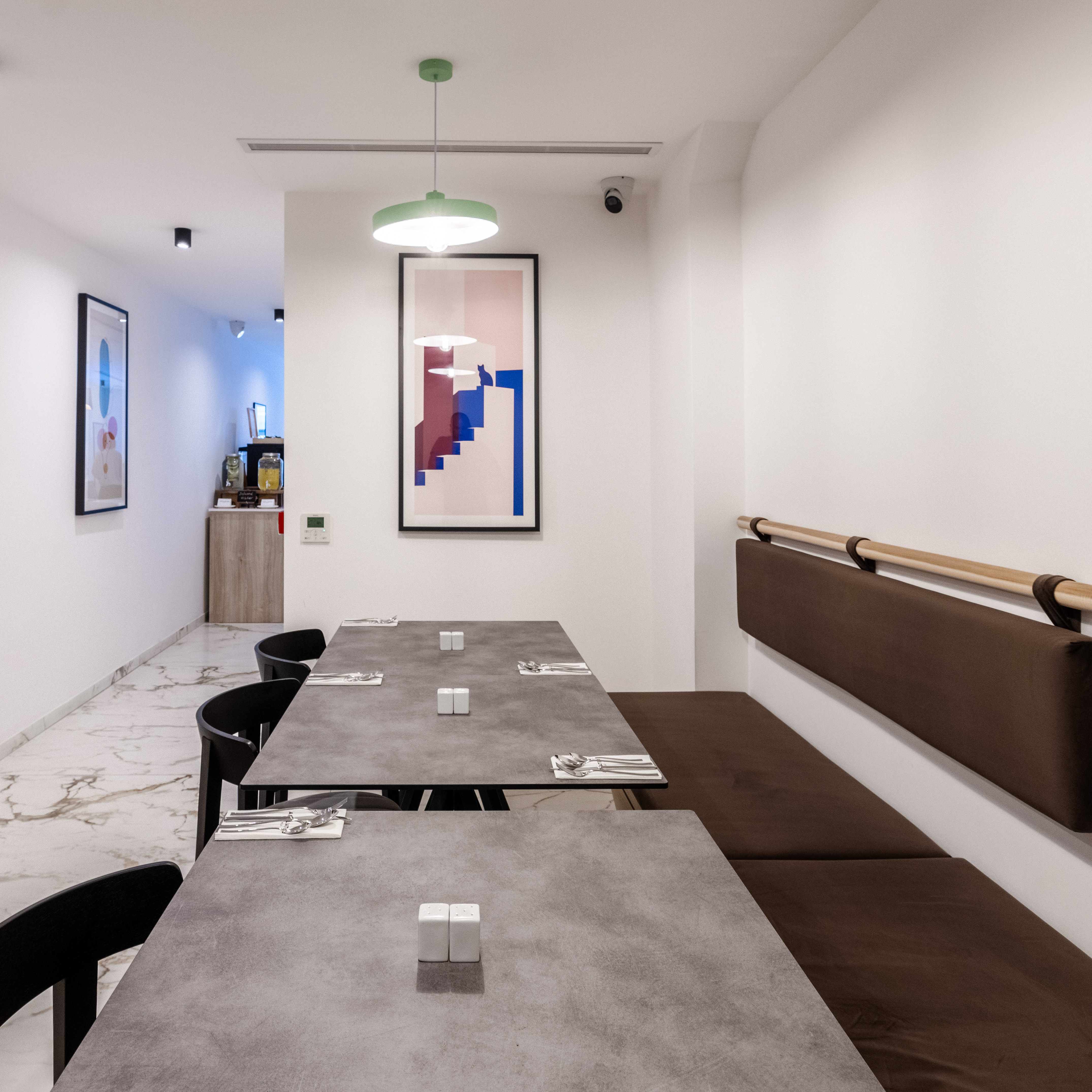 Modern restaurant with gray tables, black chairs, and brown banquette seating.