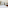 Hotel room with twin beds, sofa, desk, TV, and balcony view of mountains.