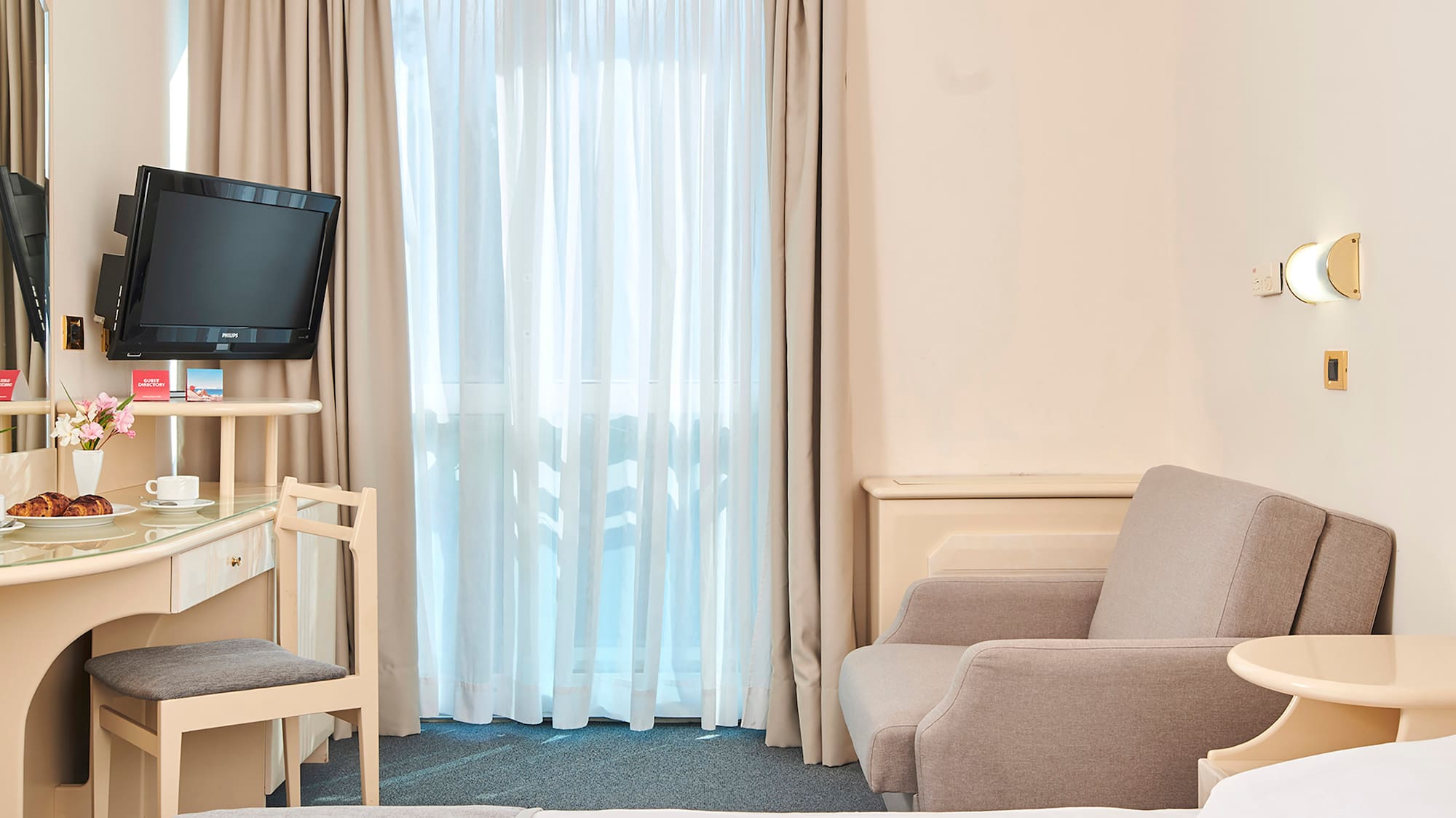 a room with a bed and a desk and a television