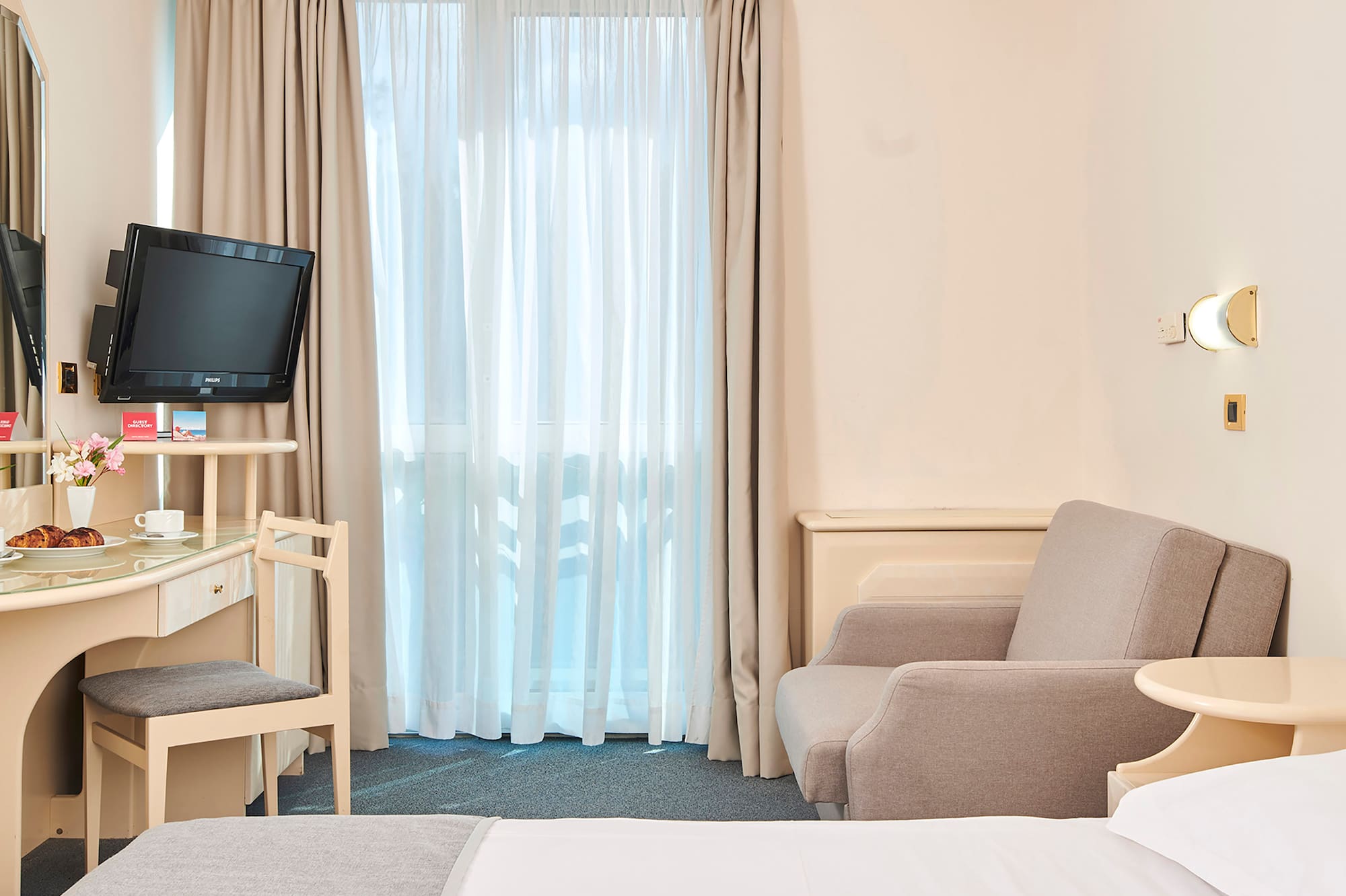 a room with a bed and a desk and a television