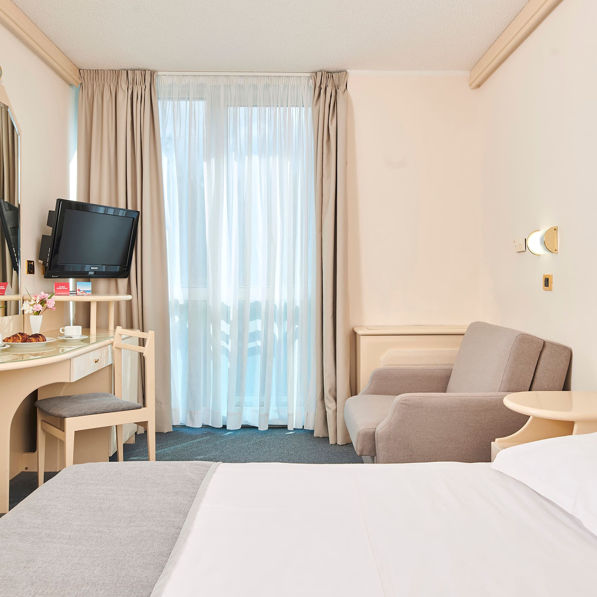 a room with a bed and a desk and a television