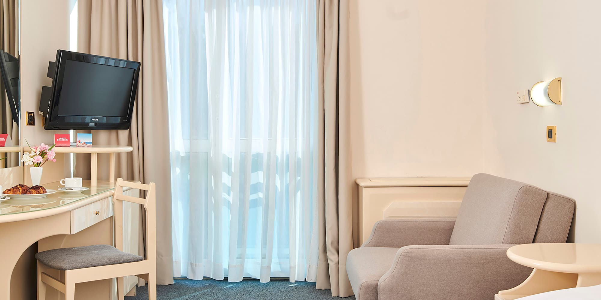 a room with a bed and a desk and a television