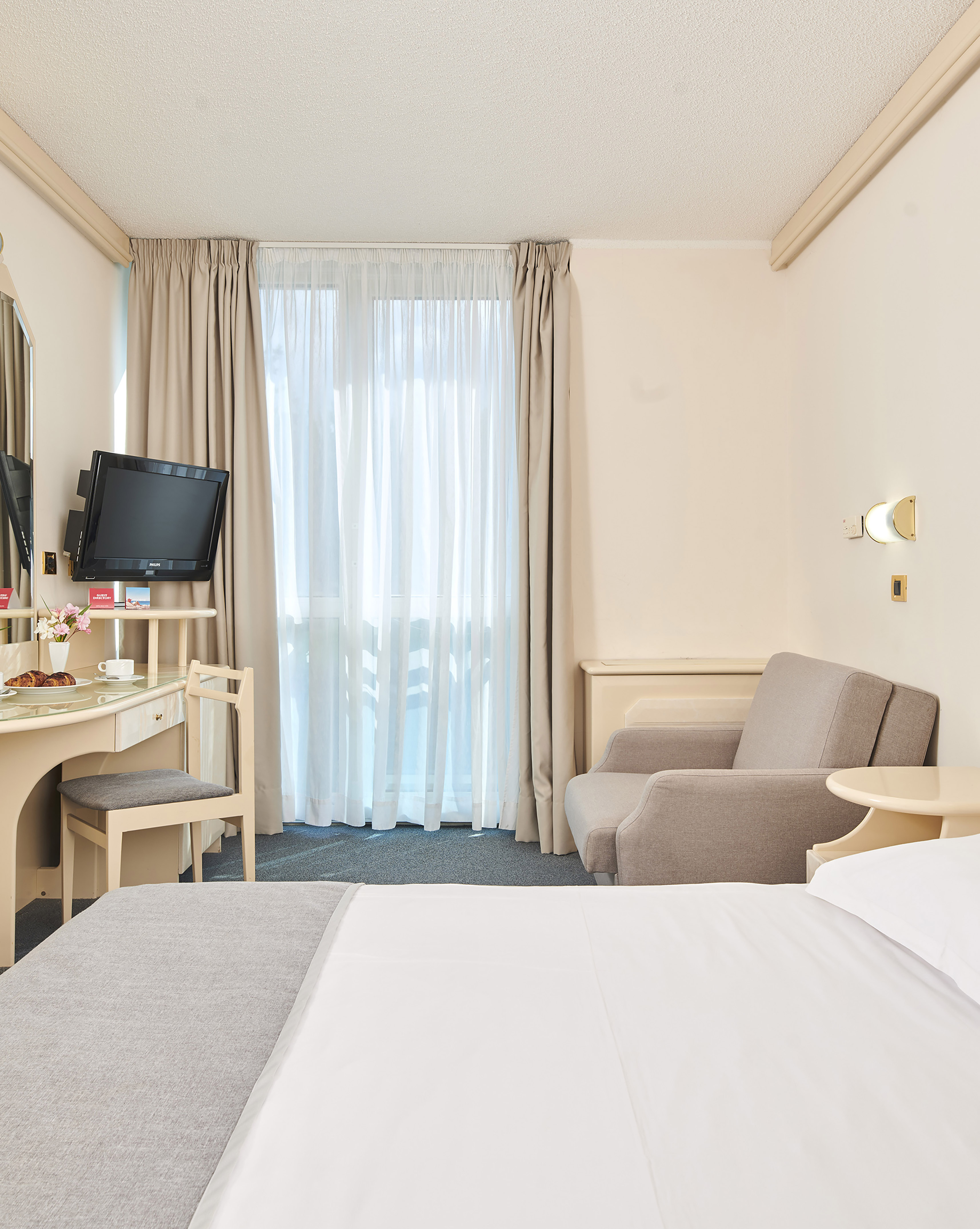 a room with a bed and a desk and a television