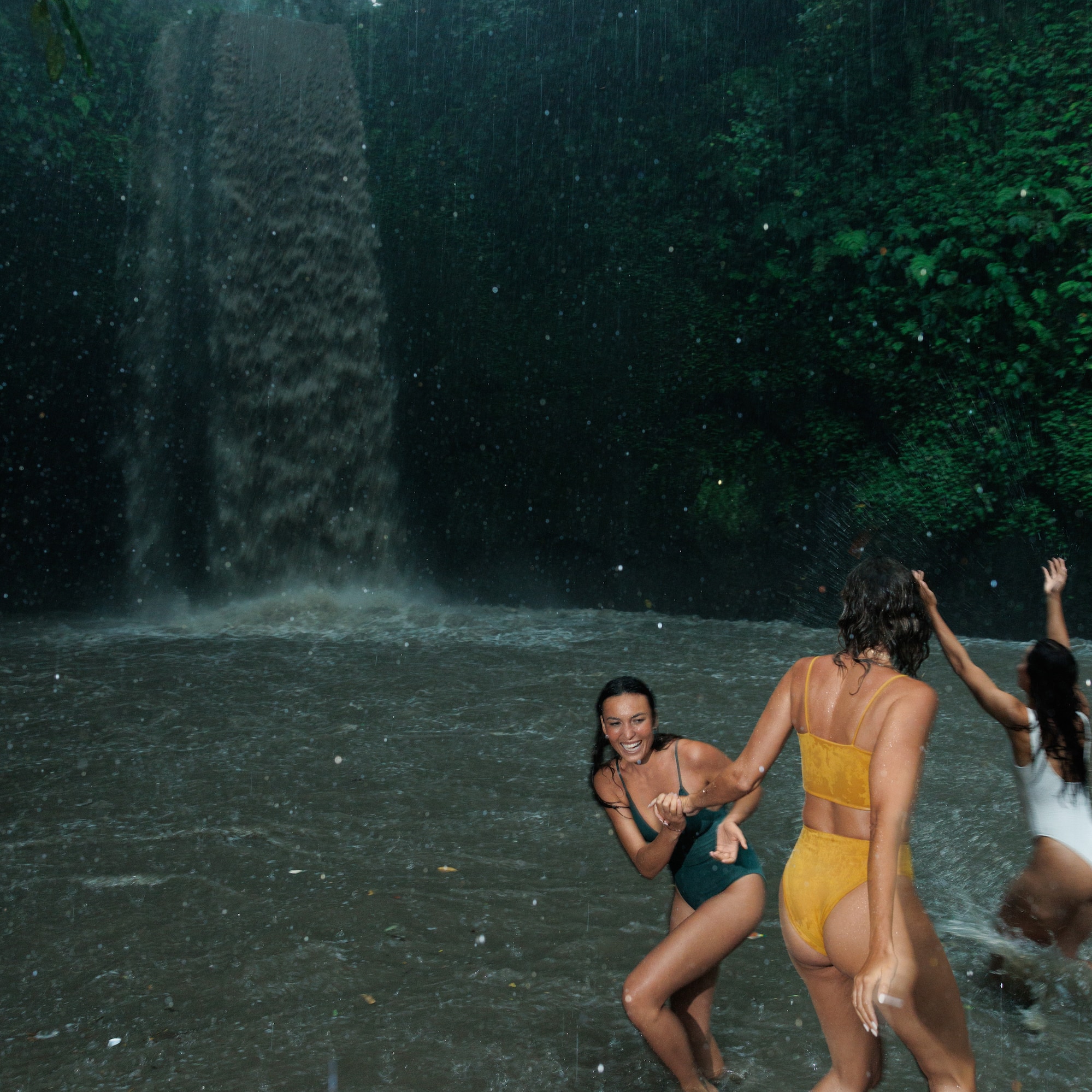 a group of women in swimsuits in a waterfall