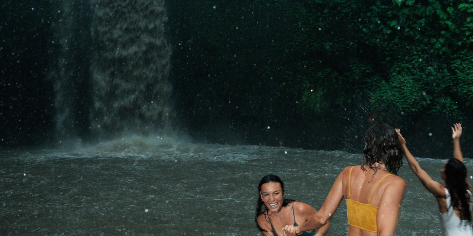 a group of women in swimsuits in a waterfall