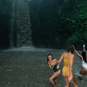 a group of women in swimsuits in a waterfall