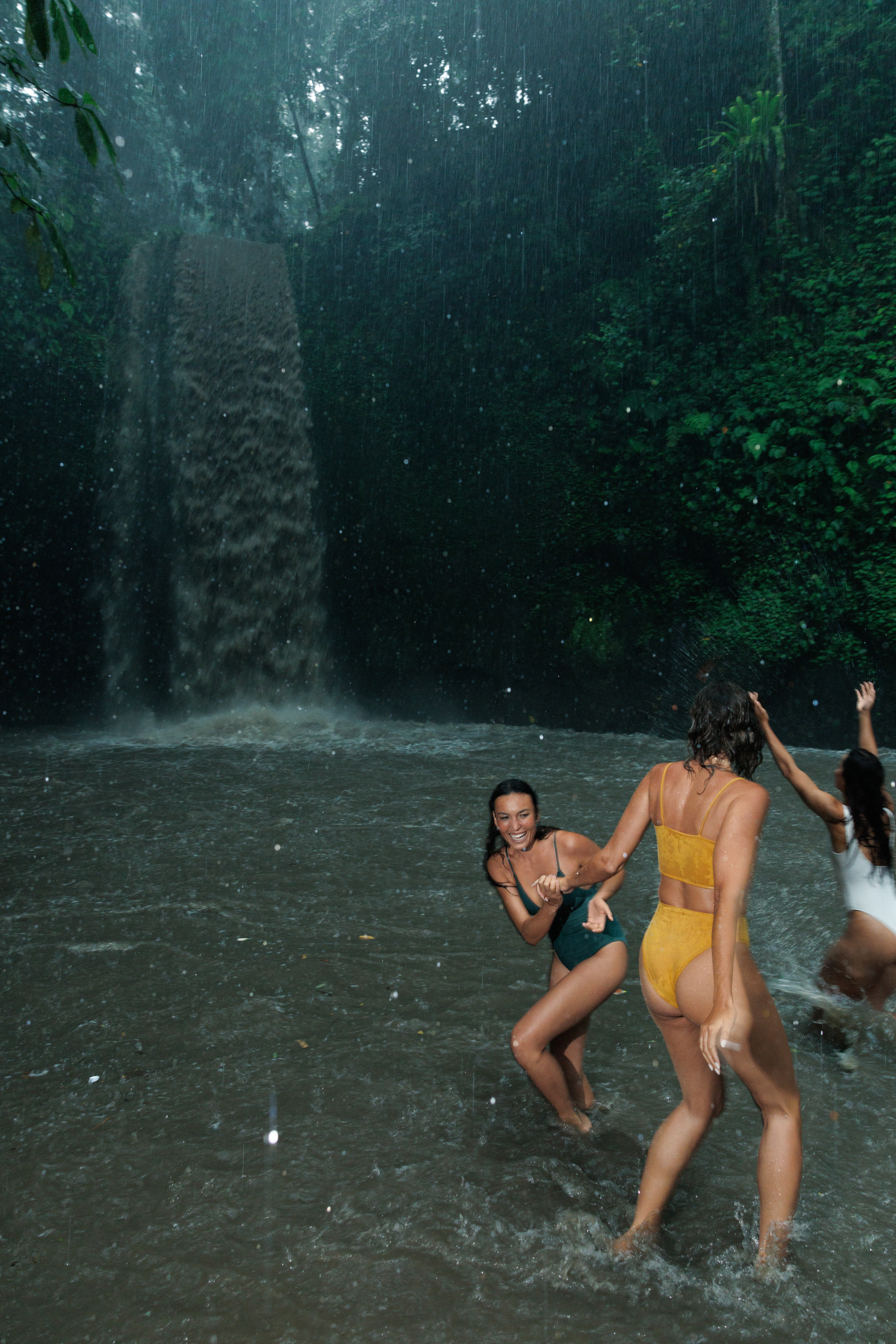 a group of women in swimsuits in a waterfall