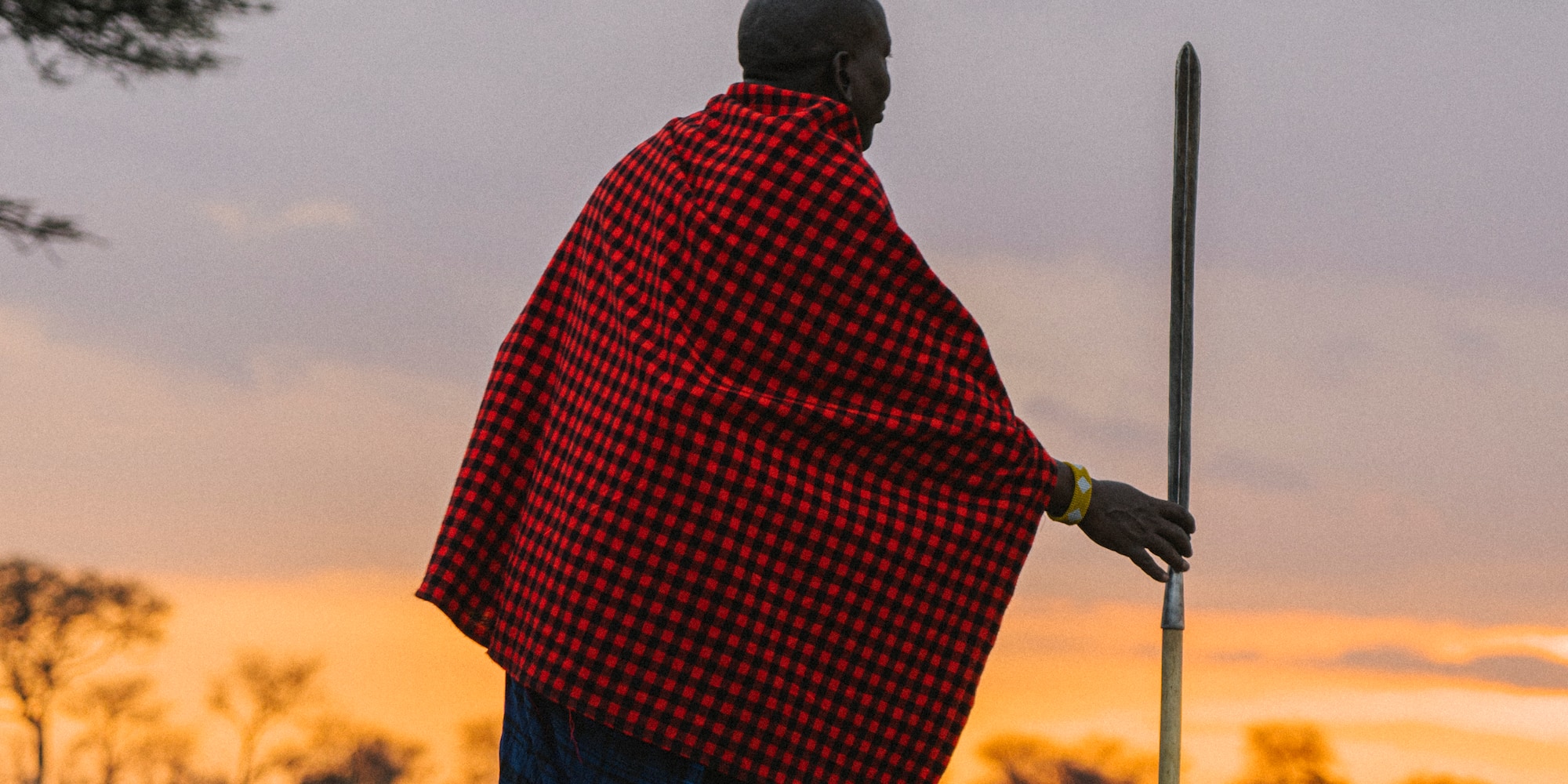 a man in a red and black plaid cape walking in a field