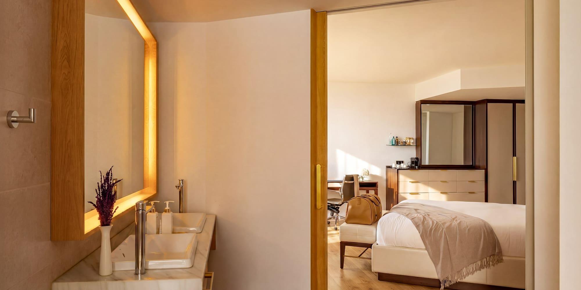 Modern hotel suite with double vanity bathroom and elegant bedroom.