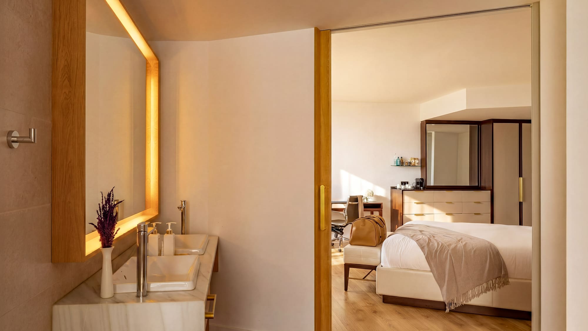 Modern hotel suite with double vanity bathroom and elegant bedroom.