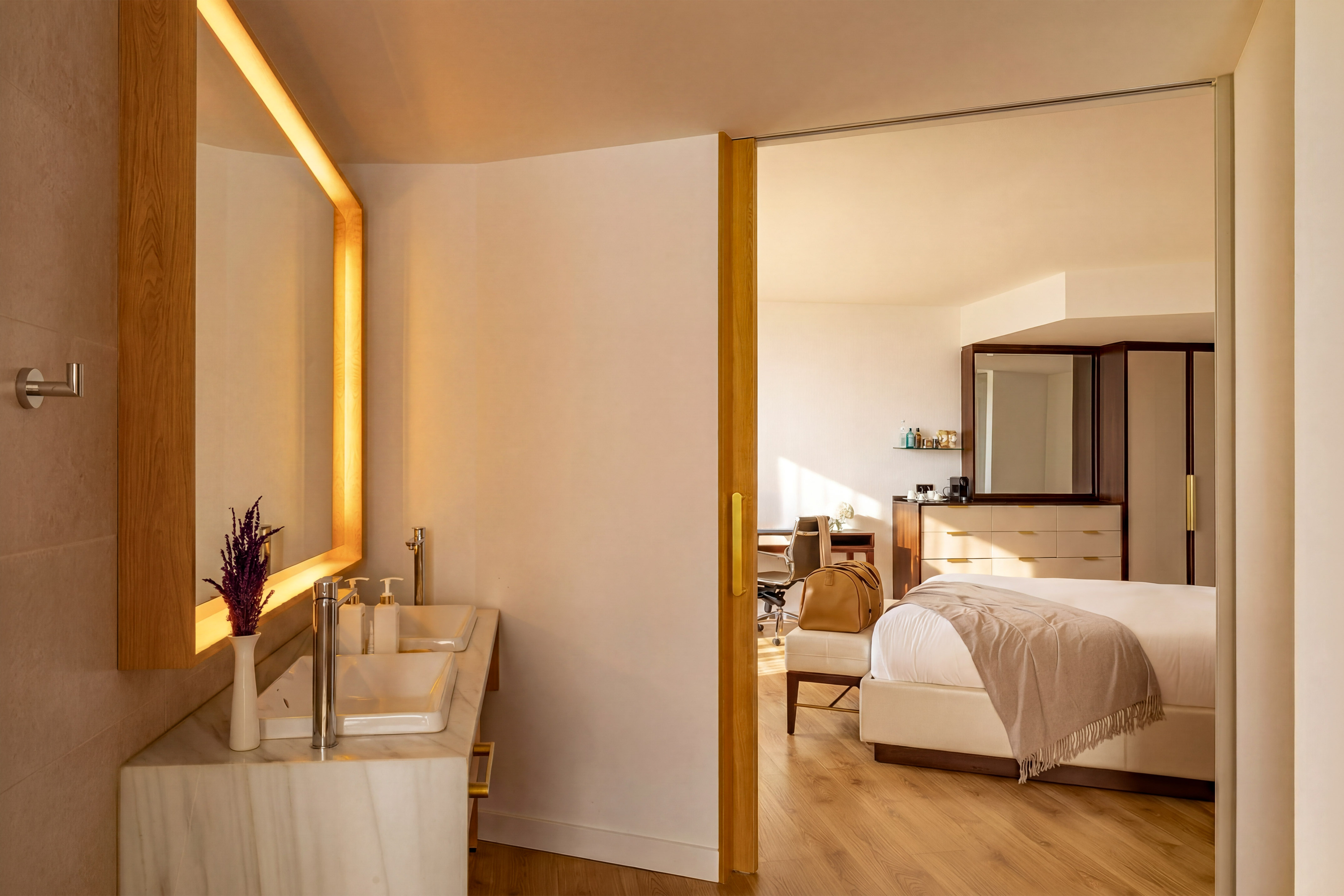 Modern hotel suite with double vanity bathroom and elegant bedroom.