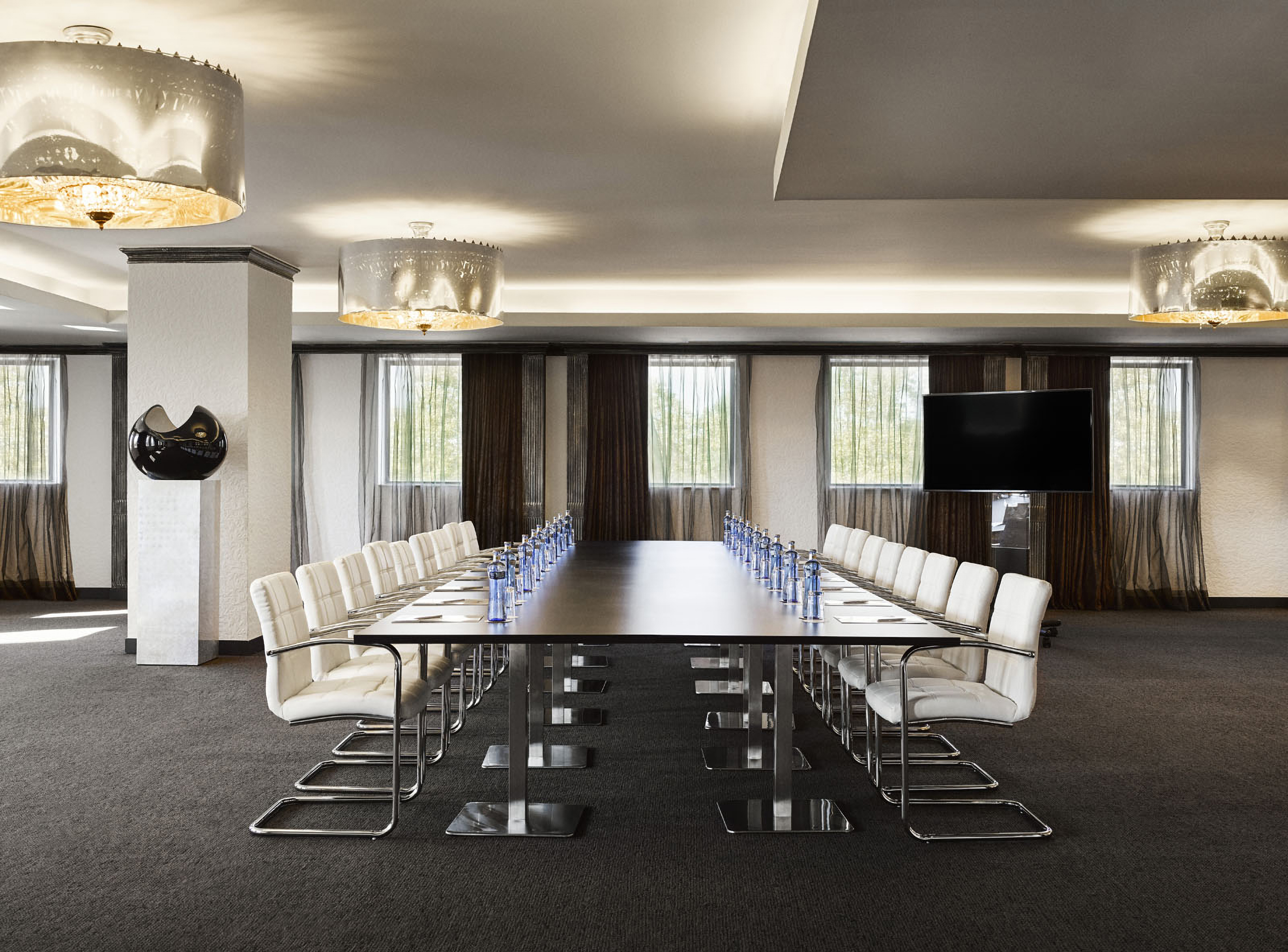 Modern conference room with long table, executive chairs, and large TV screen.