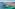 Ibiza coastal town aerial, hotels, marina, clear turquoise sea, green hills.