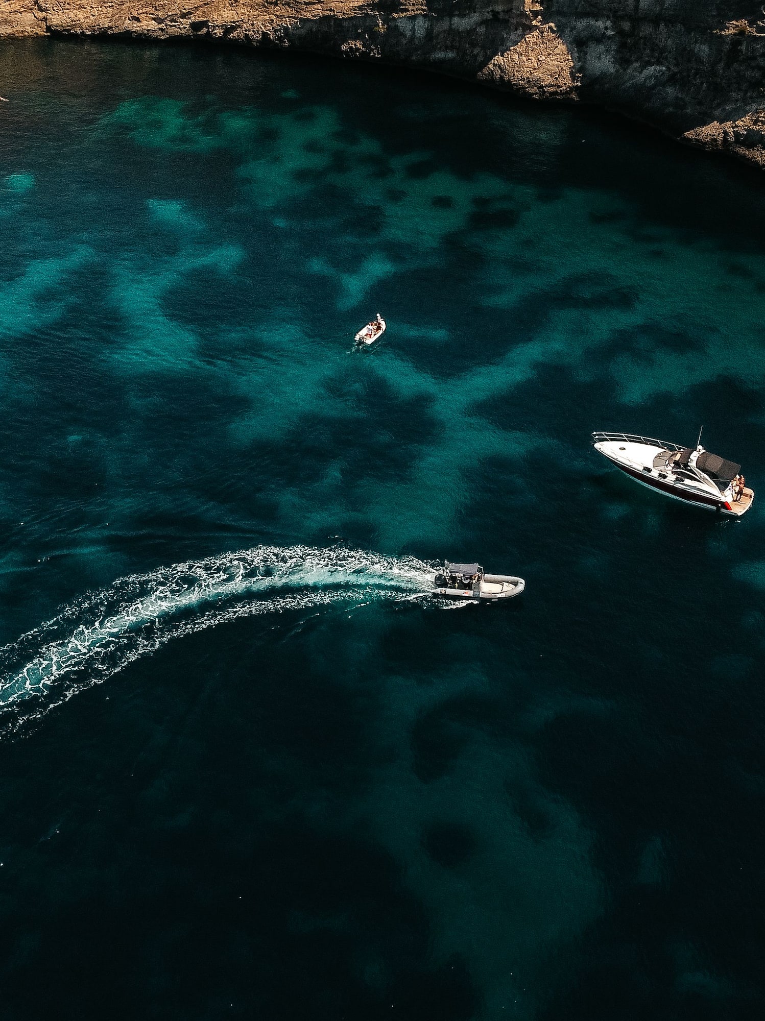 Aerial view of sailboat, yacht, speed boat in turquoise bay, rocky coast.