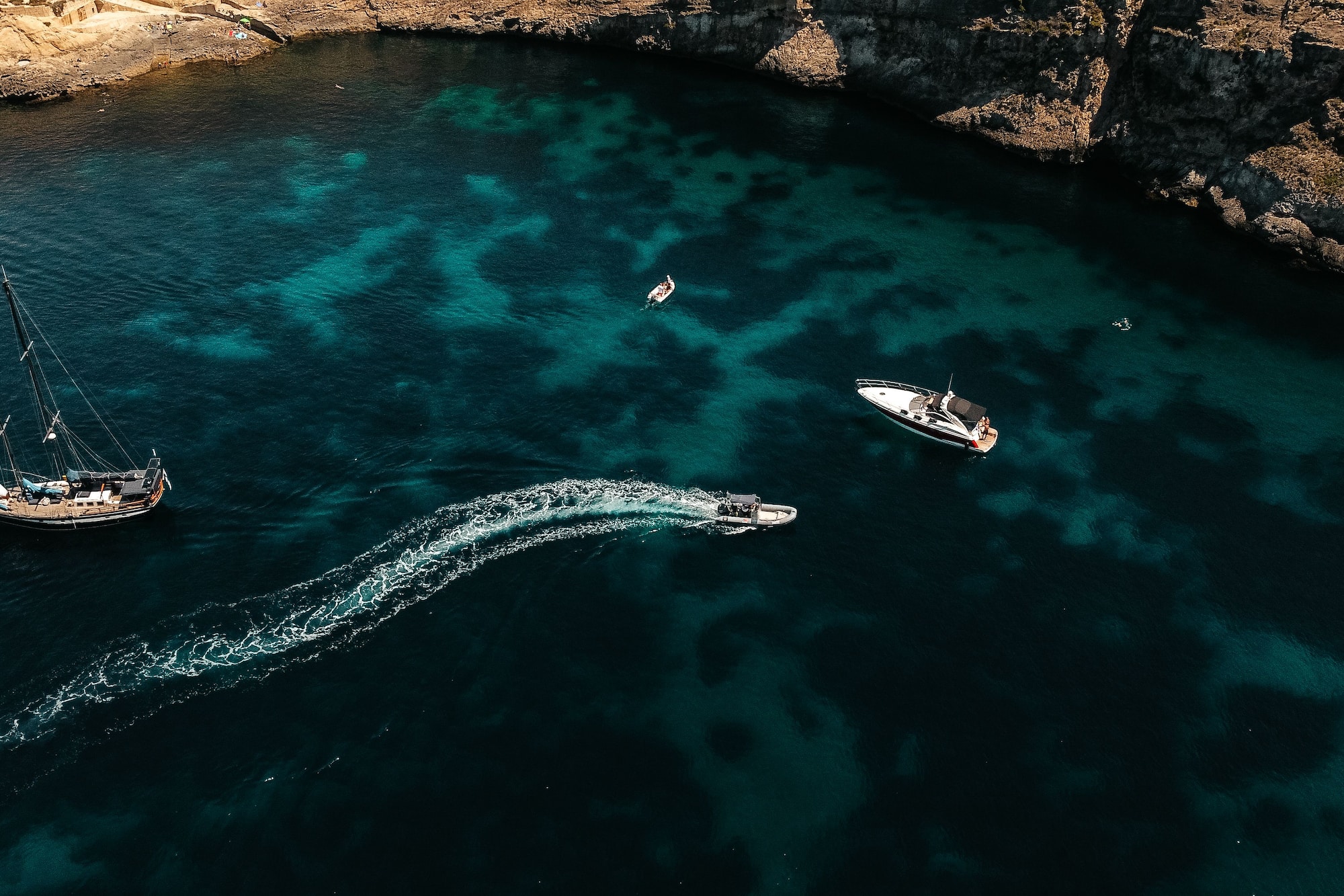 Aerial view of sailboat, yacht, speed boat in turquoise bay, rocky coast.