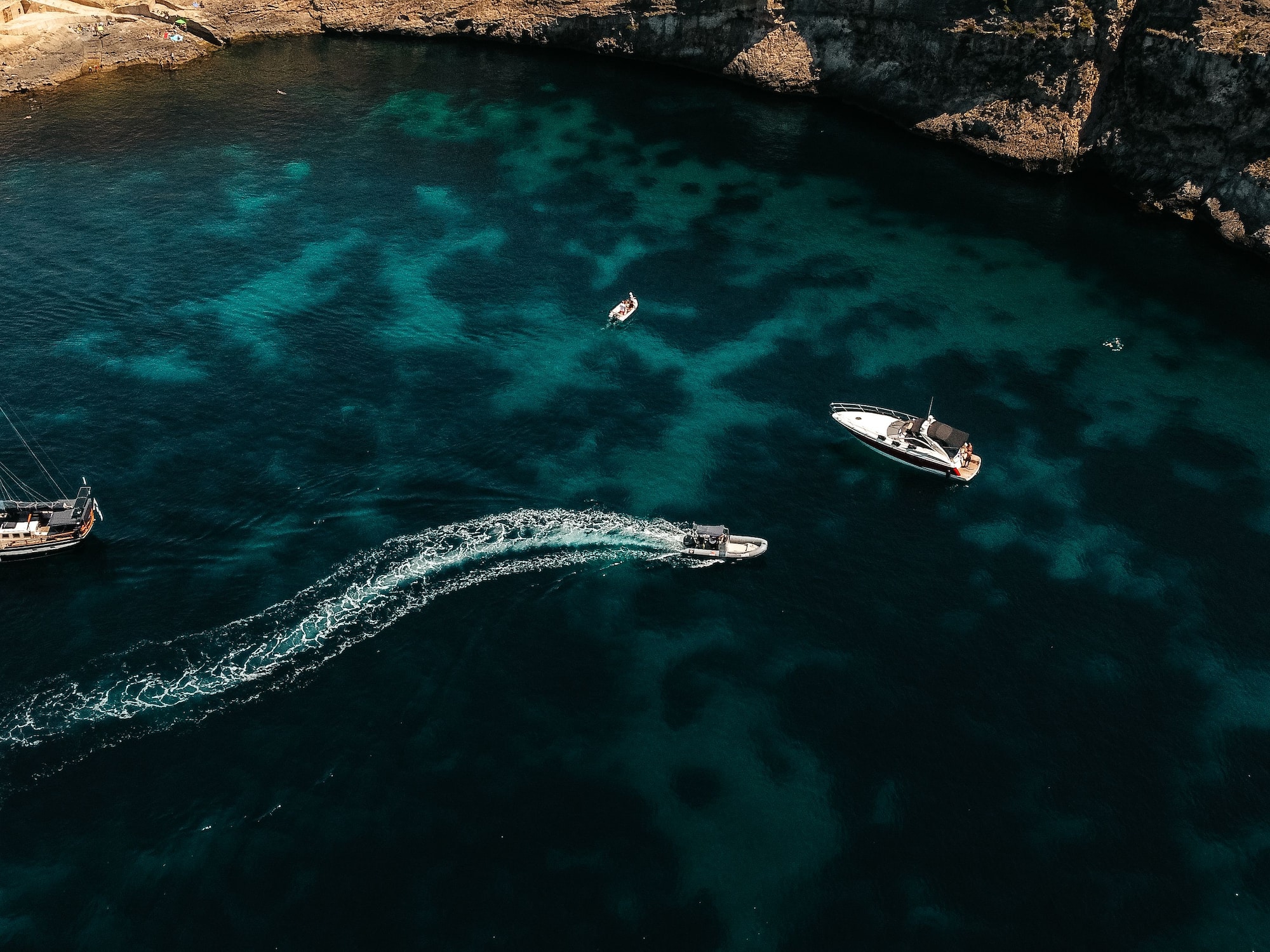 Aerial view of sailboat, yacht, speed boat in turquoise bay, rocky coast.