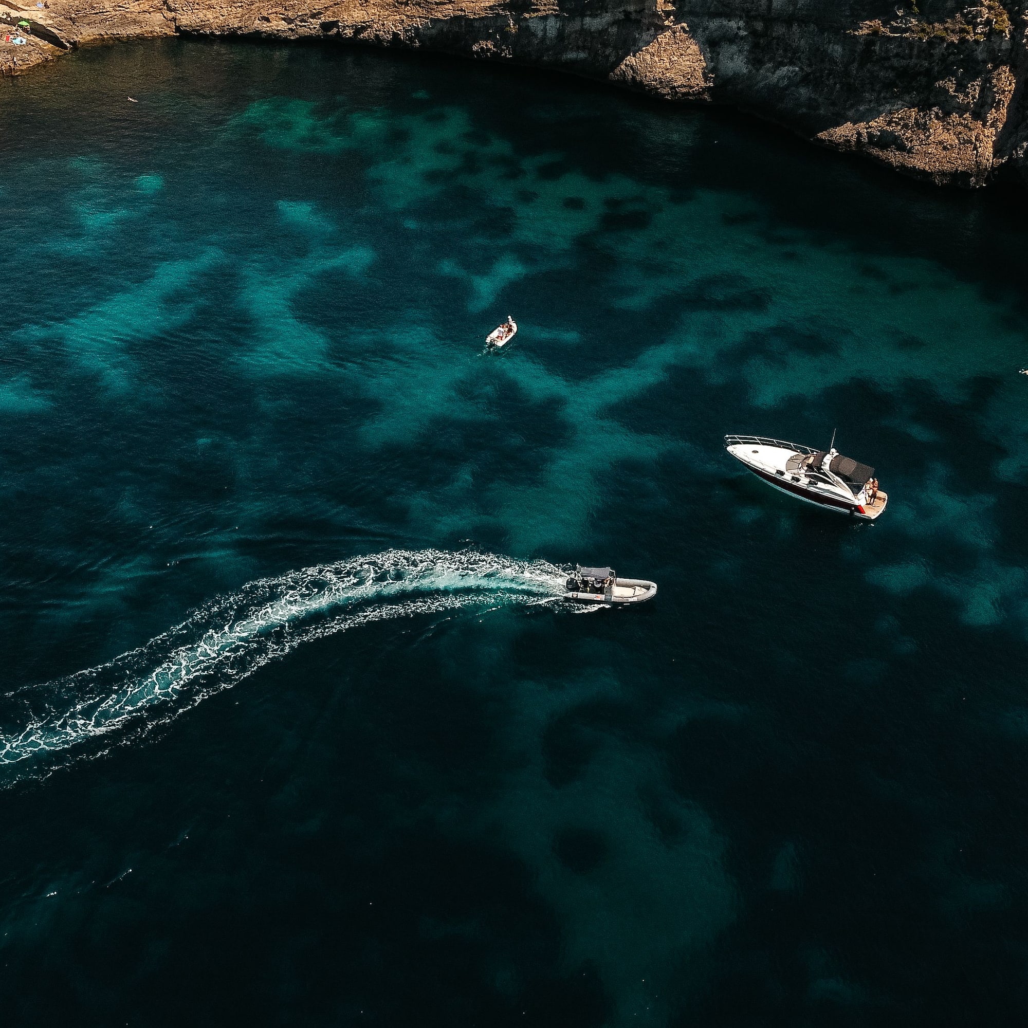 Aerial view of sailboat, yacht, speed boat in turquoise bay, rocky coast.
