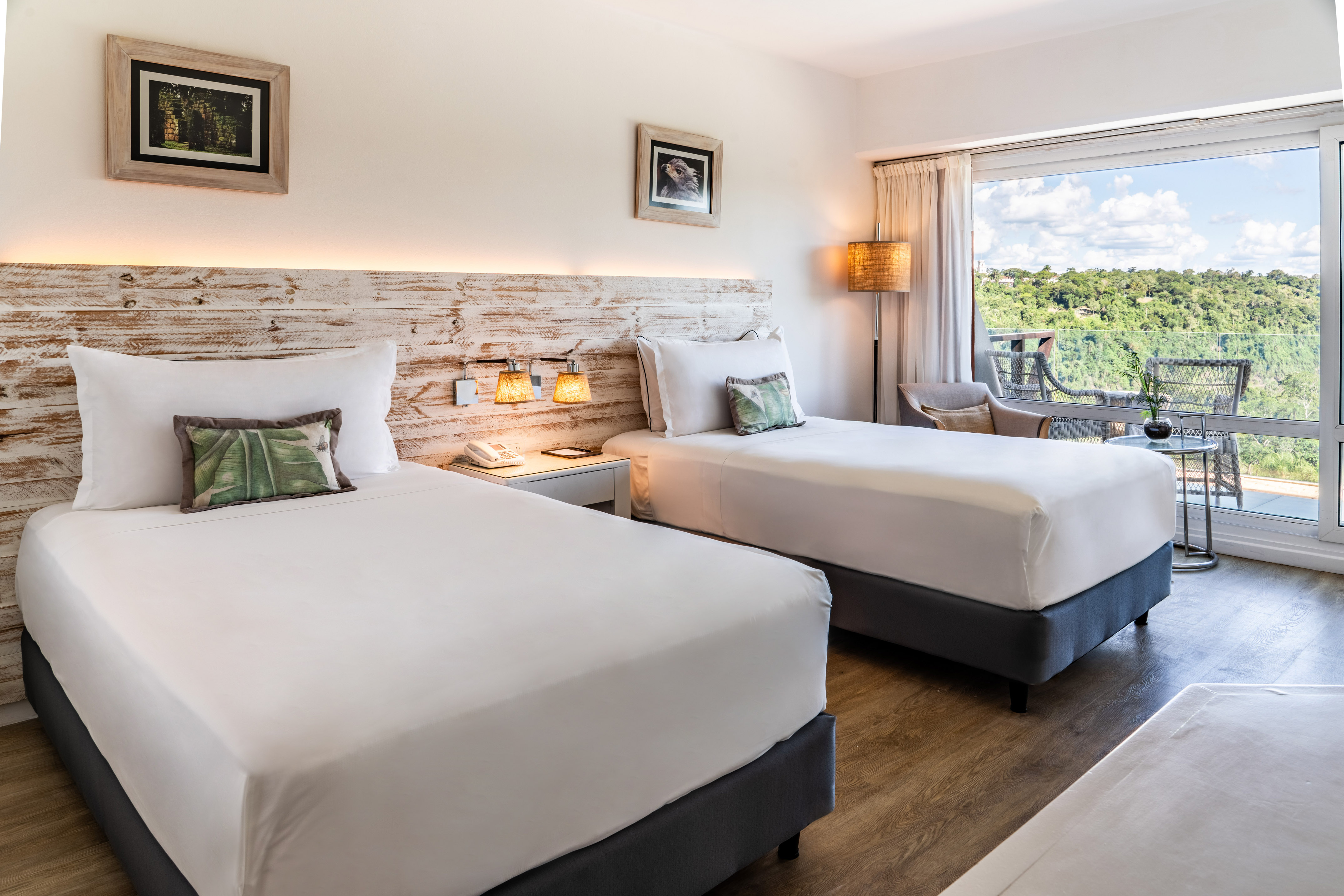 Hotel room with two beds, rustic wooden headboard, and balcony forest view.