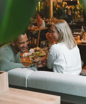 a man and woman sitting at a table with food