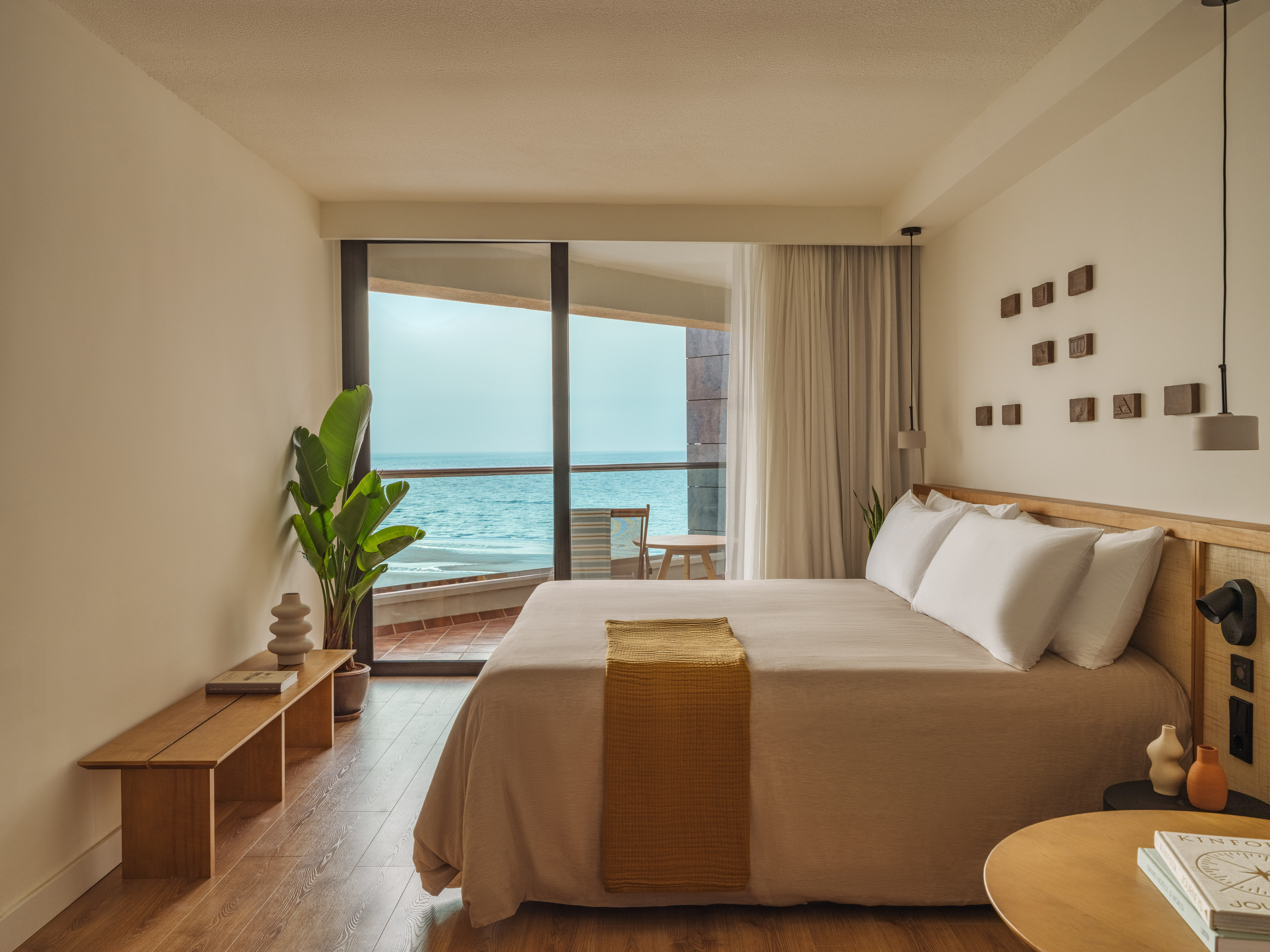 Modern beachfront hotel bedroom with ocean view balcony, and minimalist decor.