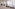 Modern reception lobby with glass partition, sheer curtains, and a waiting bench.