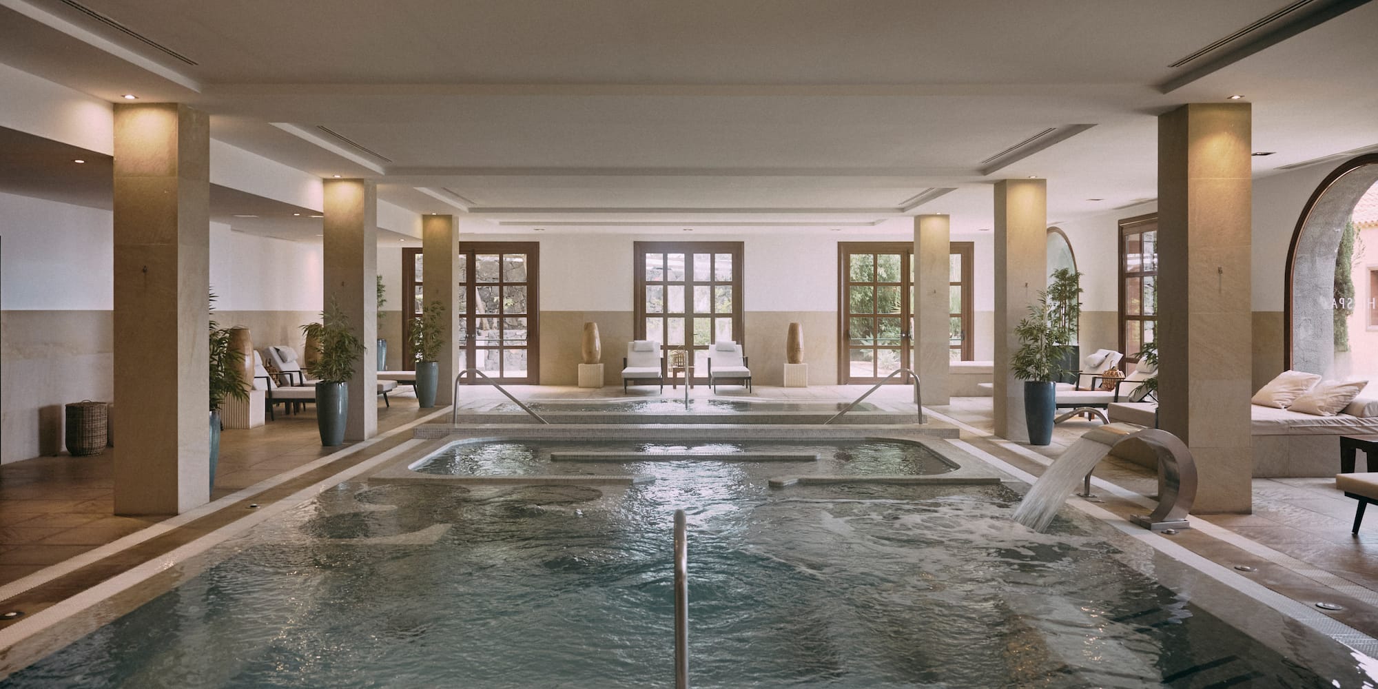 a large indoor pool with a hot tub and chairs