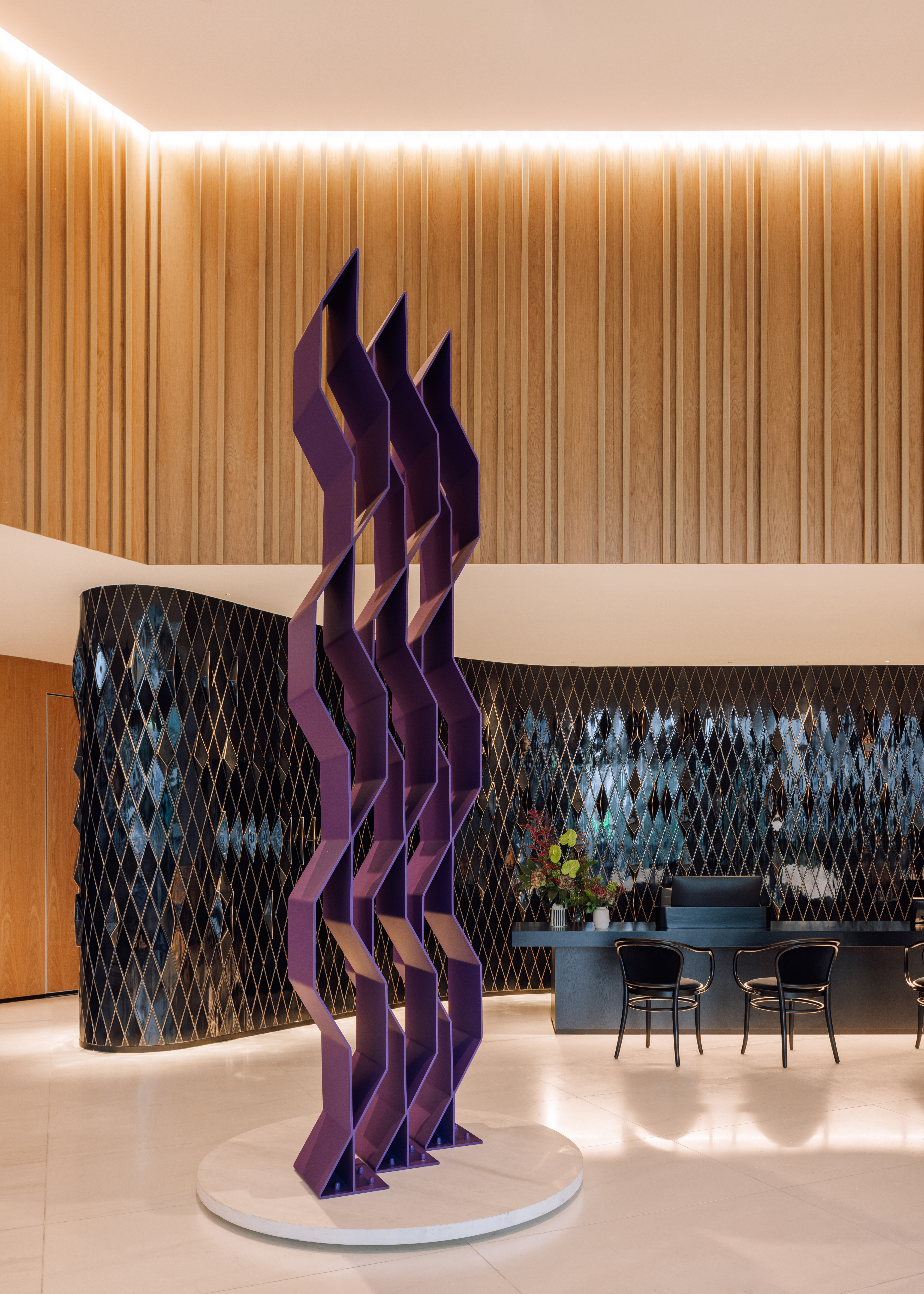 Purple abstract sculpture in modern hotel lobby. Wood walls, black tiled reception.