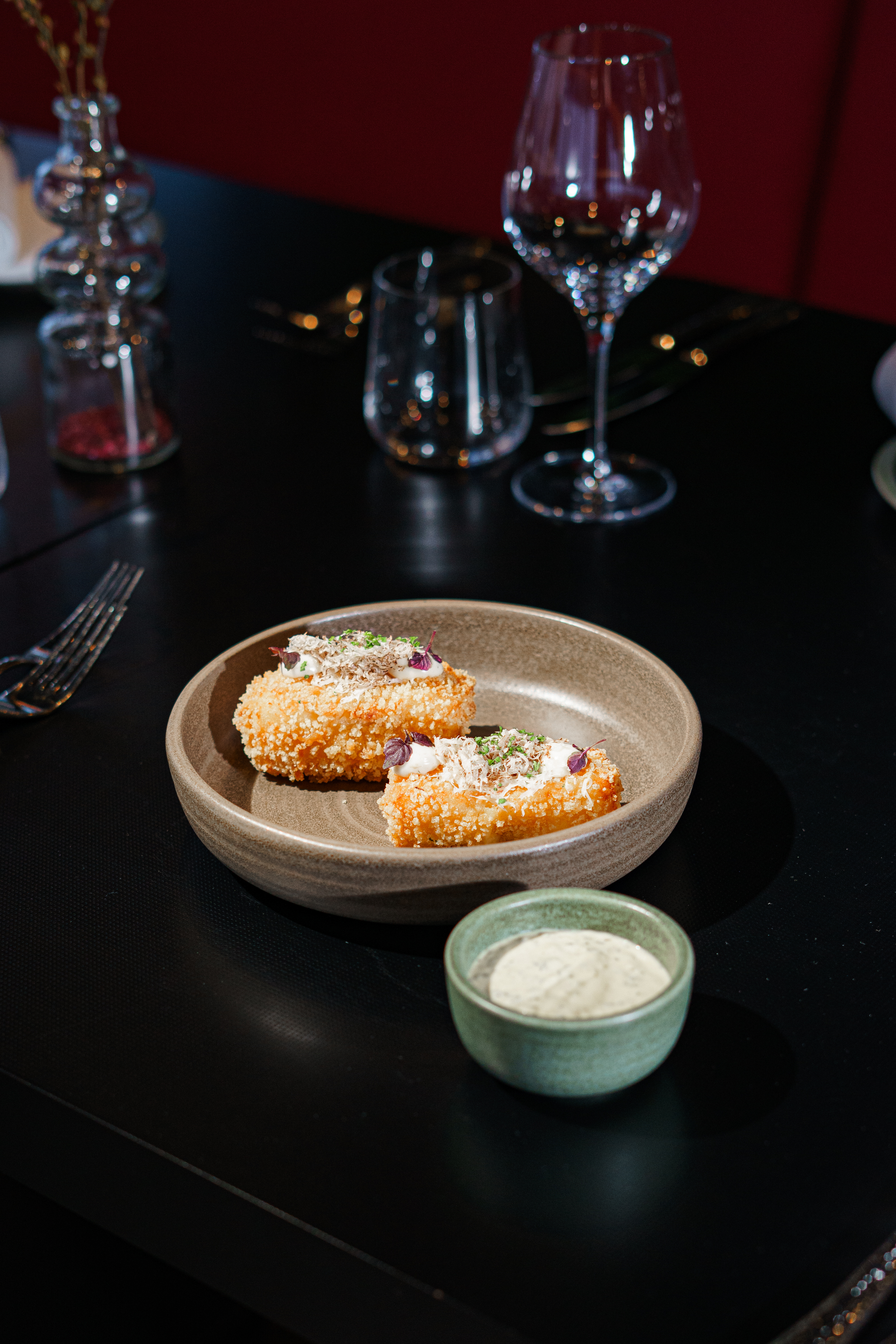 Crispy truffle croquettes with dipping sauce on a dark restaurant table.