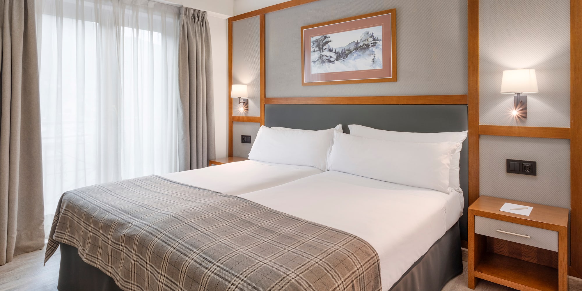 a bed with a blanket and a picture on the wall