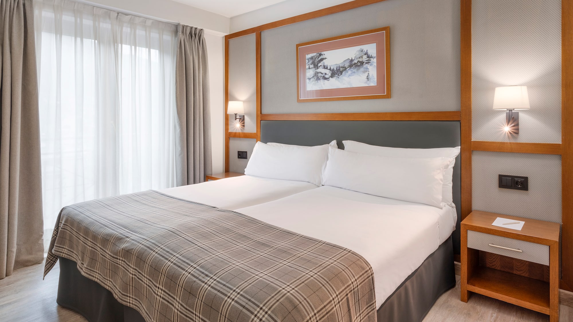 a bed with a blanket and a picture on the wall