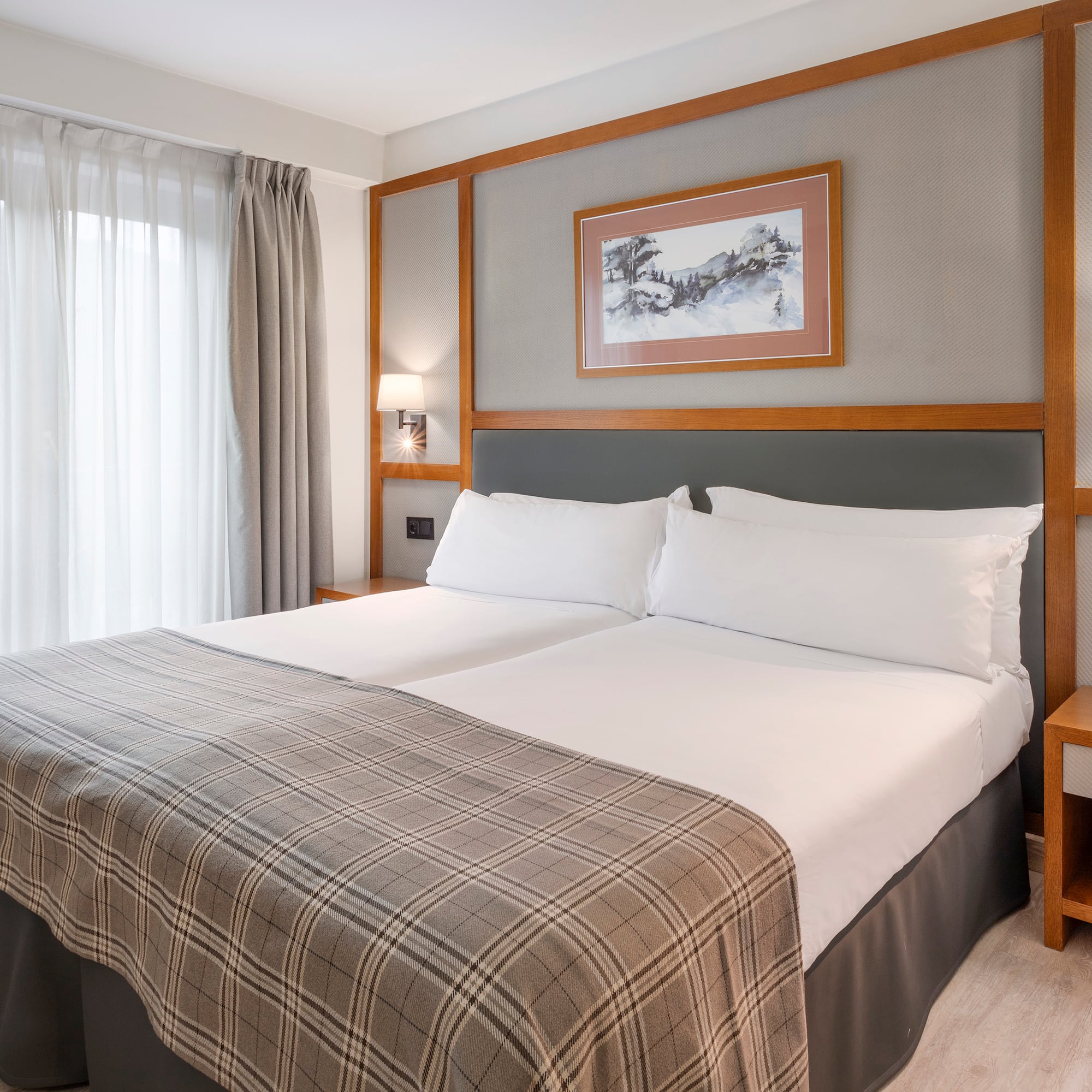 a bed with a blanket and a picture on the wall