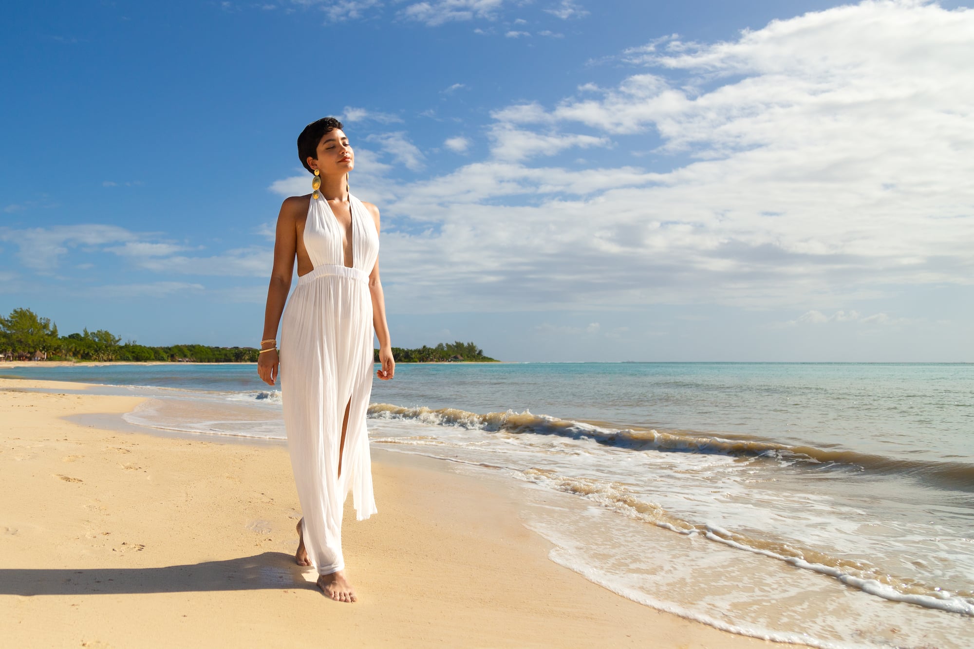 a woman in a white dress walking on a beach