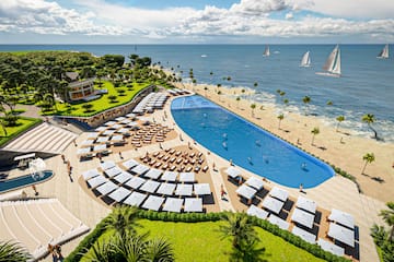 a pool and beach with palm trees and people on it
