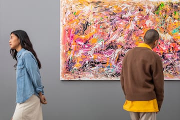 a man and woman looking at a painting