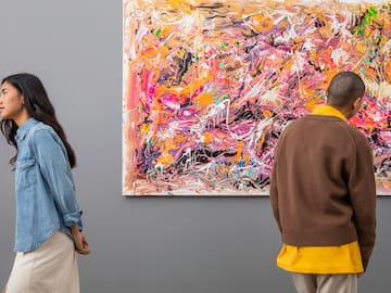 a man and woman looking at a painting